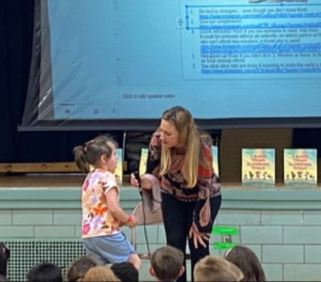 Michelle Figueroa holds a microphone out to a child while on tour to teach kids kindness.