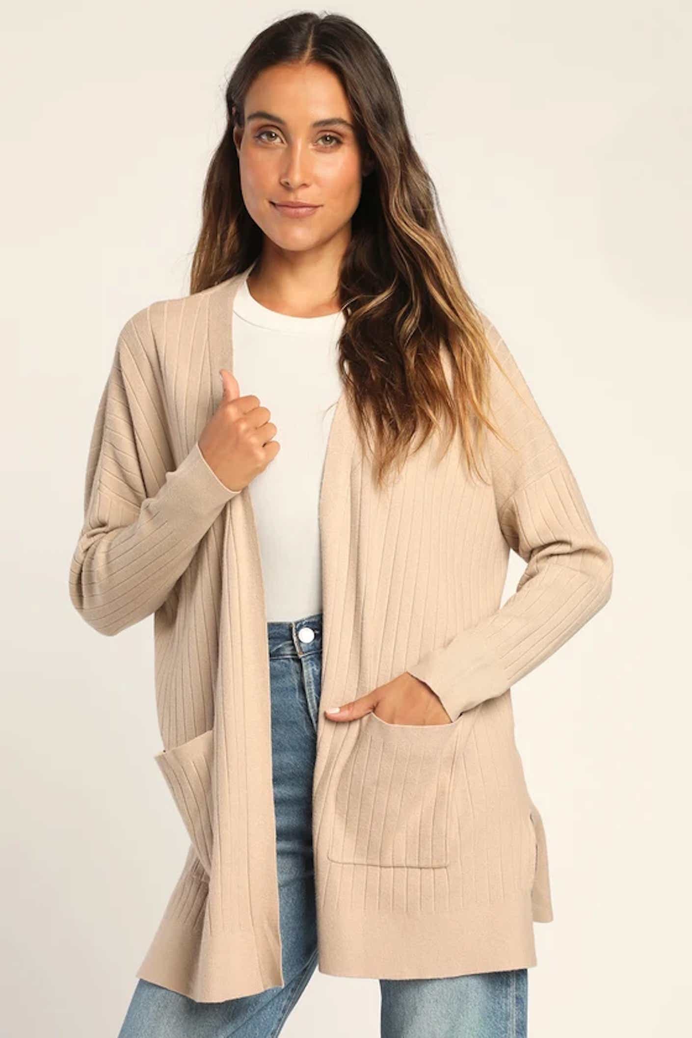 A woman wears a long, open front, ribbed, taupe cardigan.