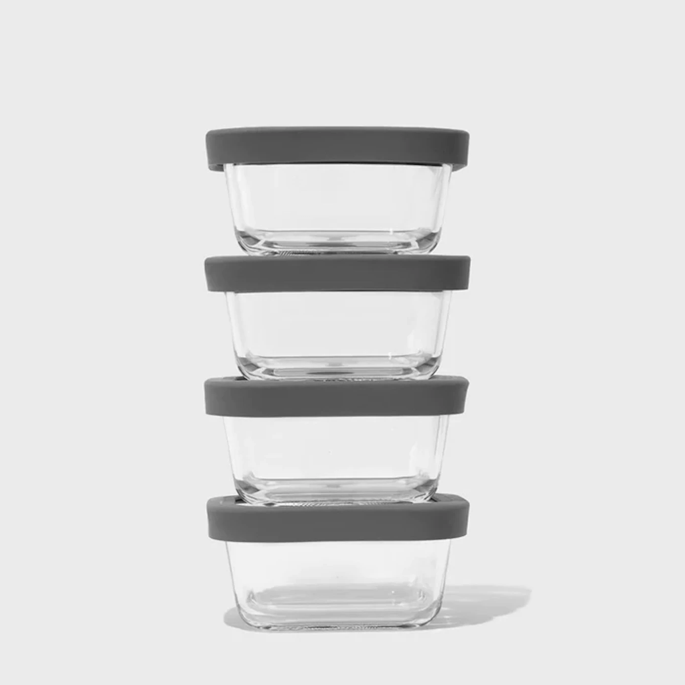 Four clear food storage containers sit stacked on top of one another.