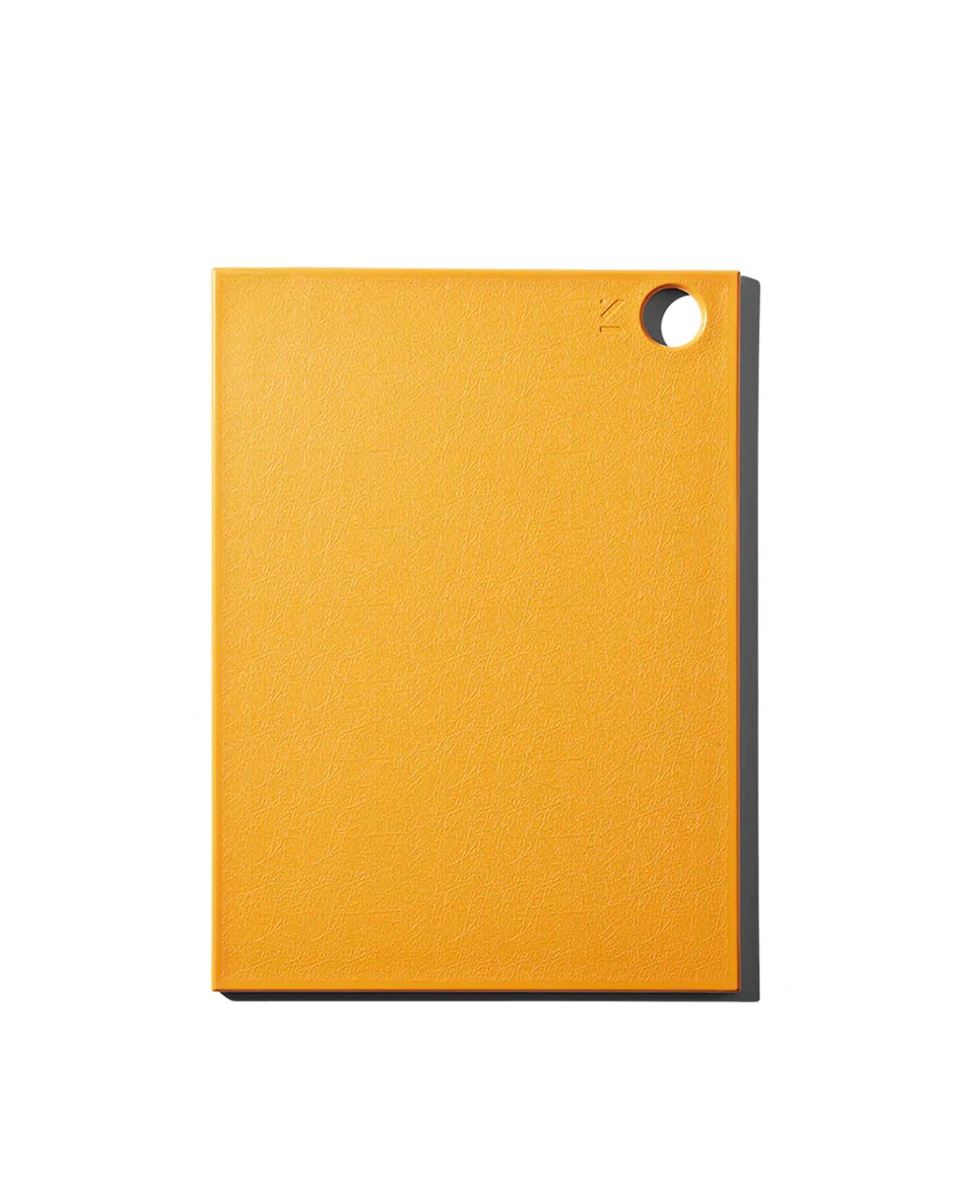 A yellow-orange cutting board with a hole (for hanging if needed) in the corner is shown flat.