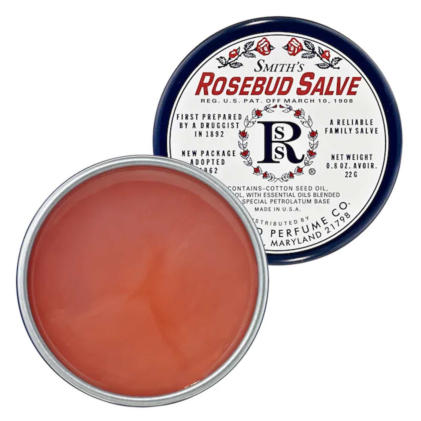 A tin is open to reveal peachy pink salve.