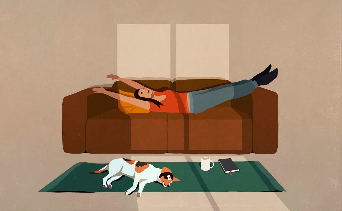 A woman stretches happily on a couch as a cat sleeps on a rug beneath her.
