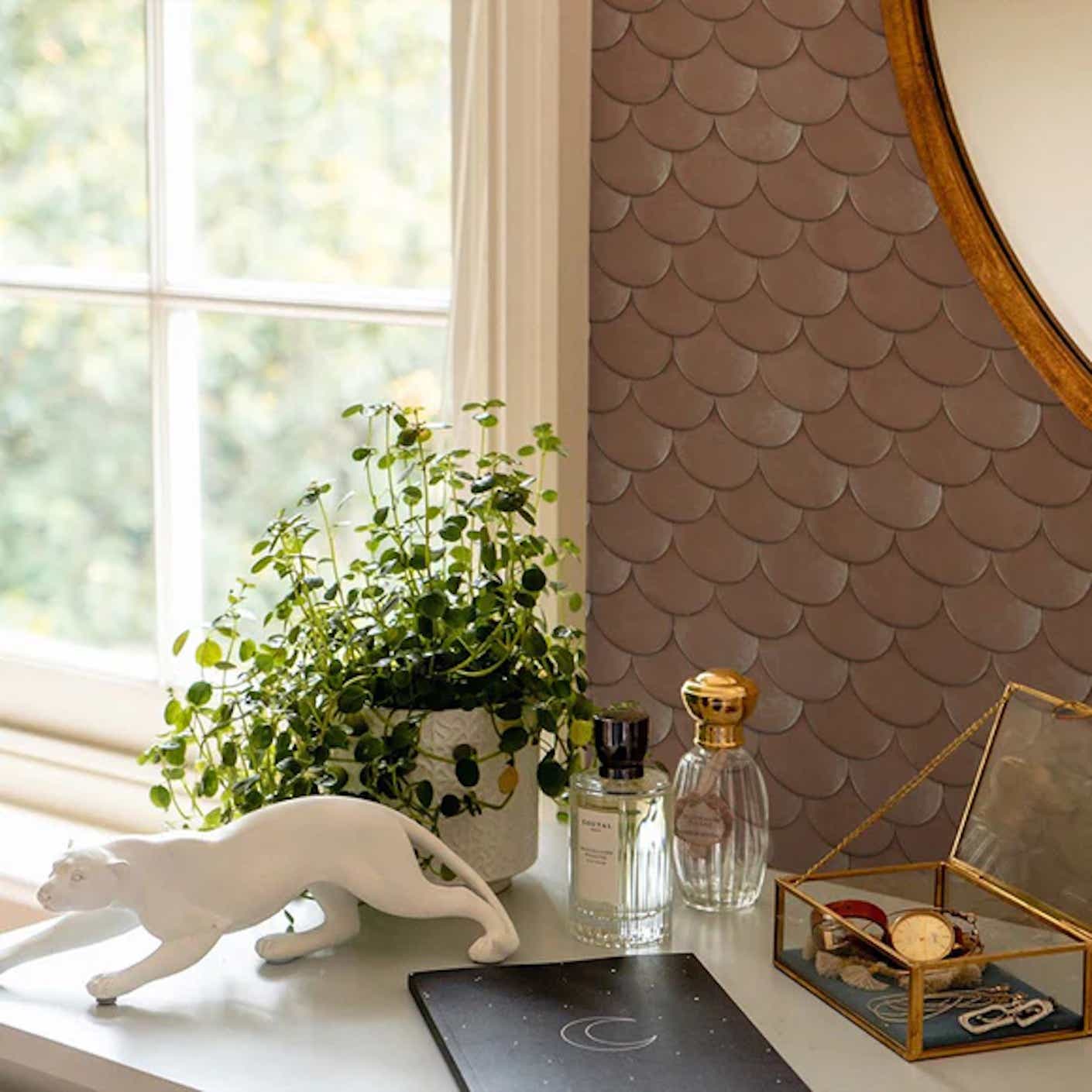 A nightstand is pictured in the foreground while in the background you can see brass, metallic, fish scale pattern printed wallpaper.