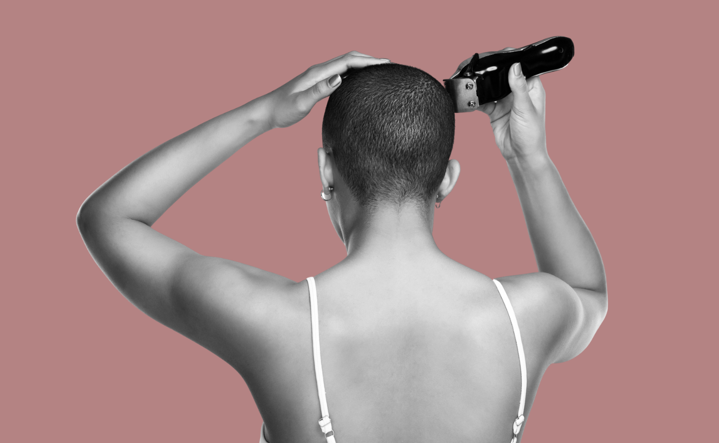 Photo taken from behind of young woman shaving her head