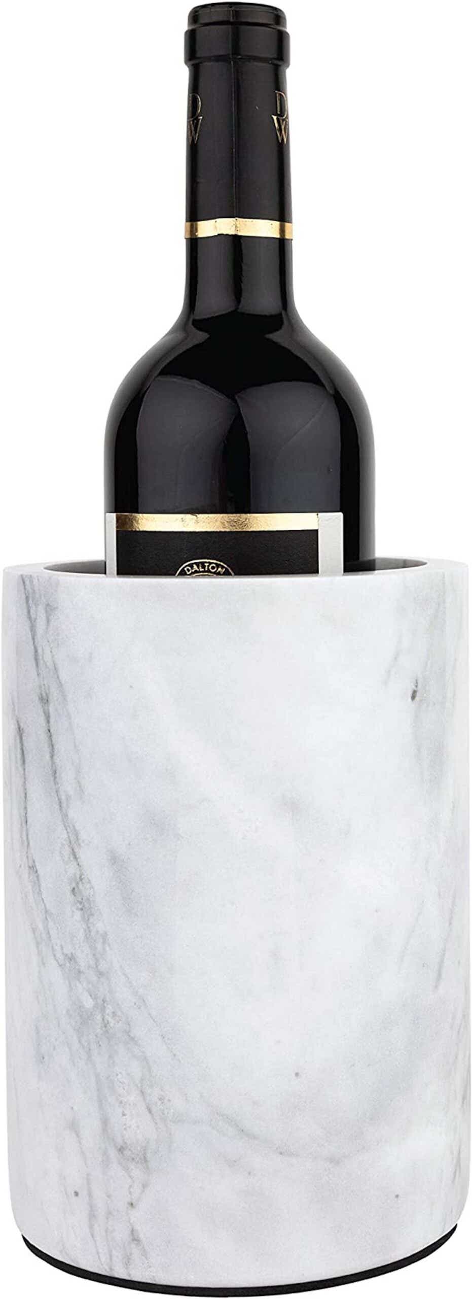A cylindrical, white, marble wine chiller sits with a bottle of wine inside of it.