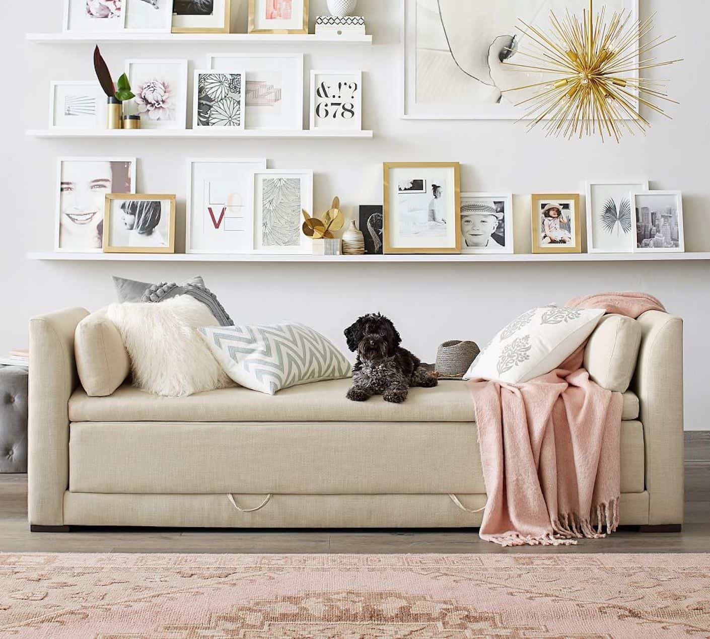 A beige daybed that converts into a sleeping space is pictured in a bright, organized living room.