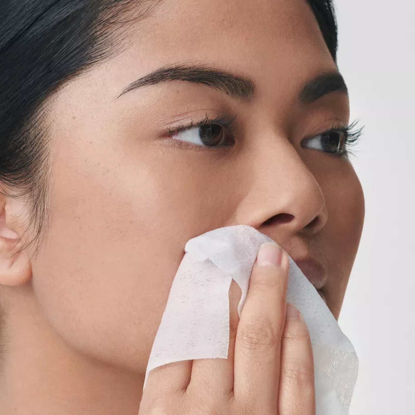 A woman holds an after-wax towel wipe up to her lip.