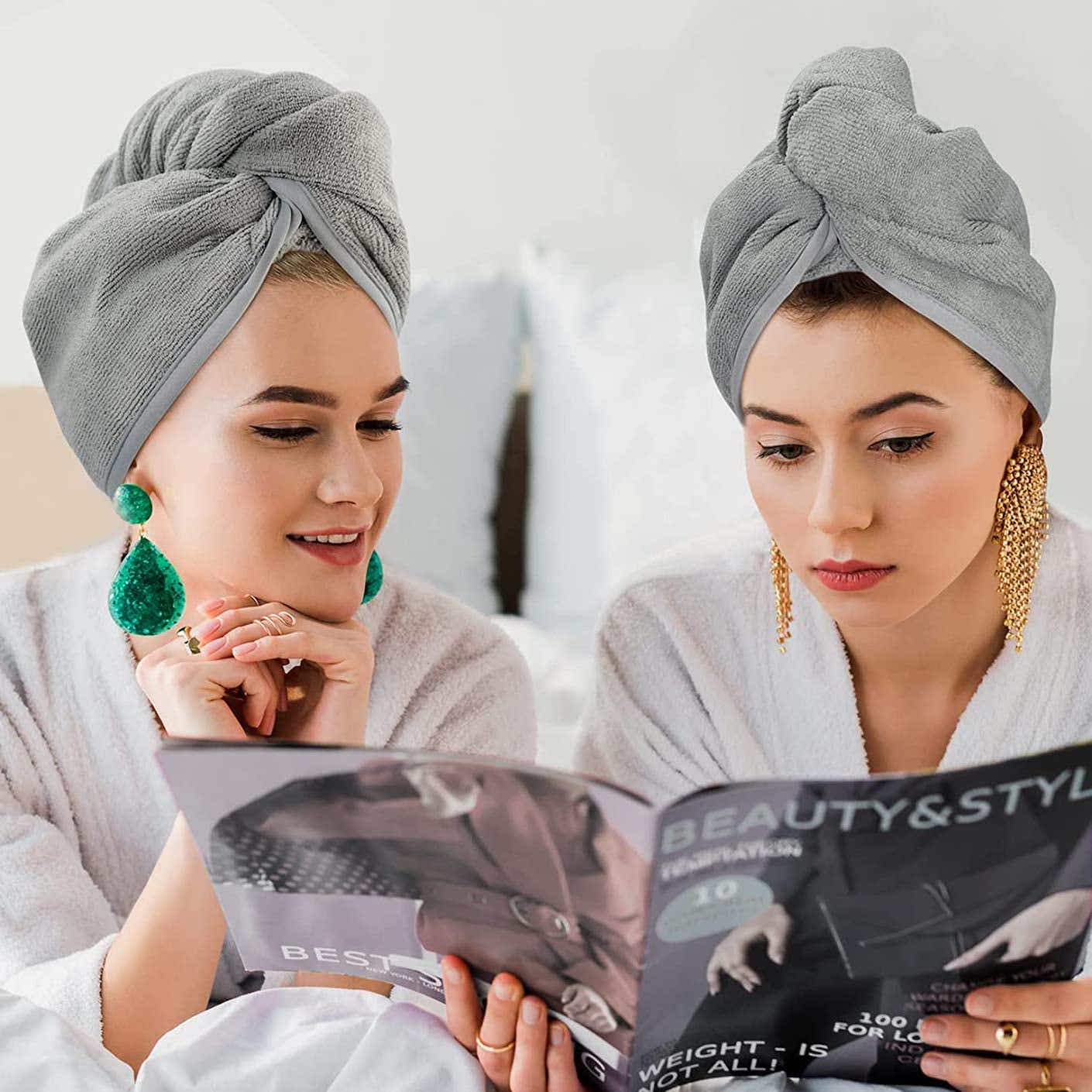 Two women look at a magazine while wearing microfiber hair wraps.