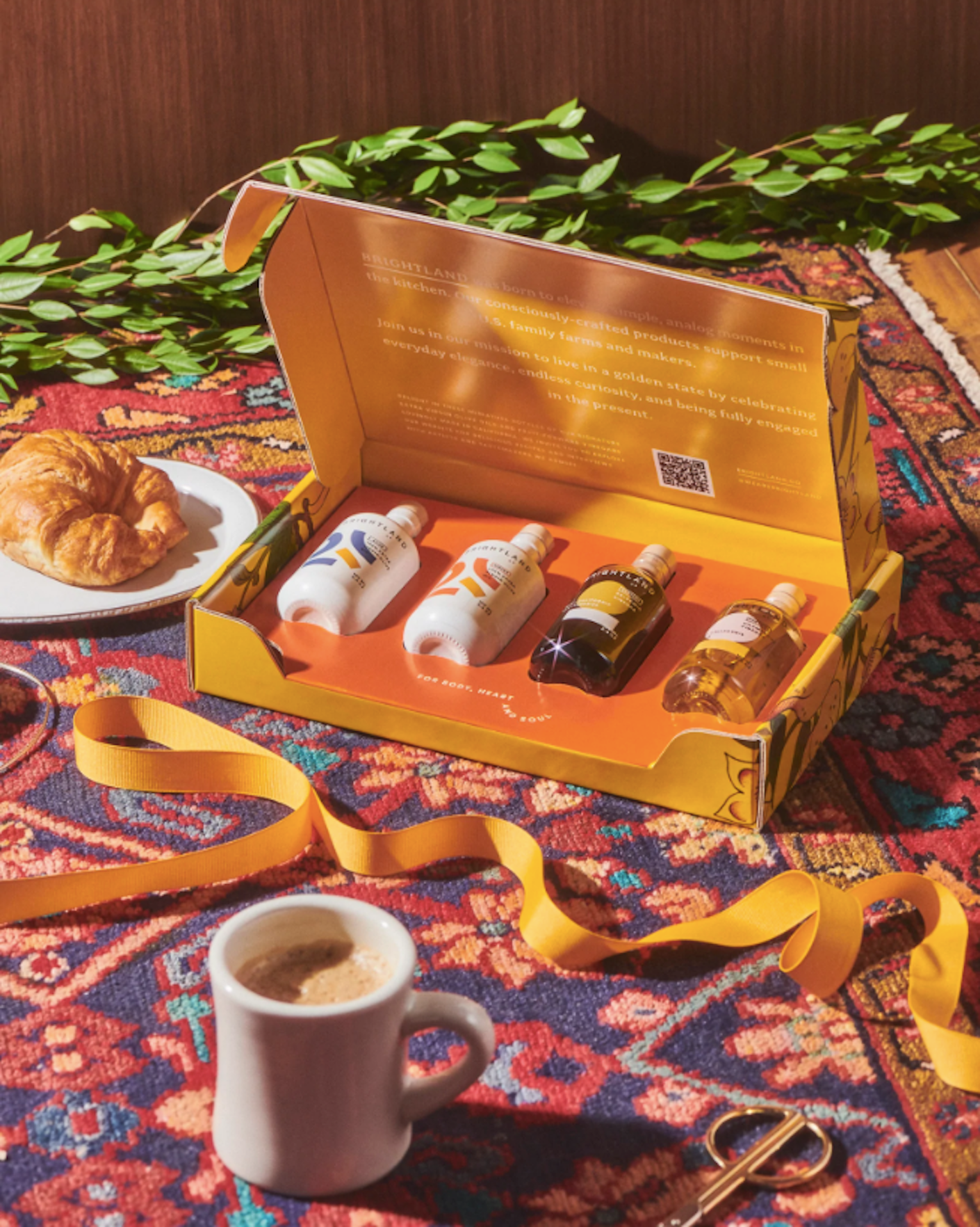 A boxed set of two olive oil bottles and two vinegar bottles sits atop a colorful kitchen table.