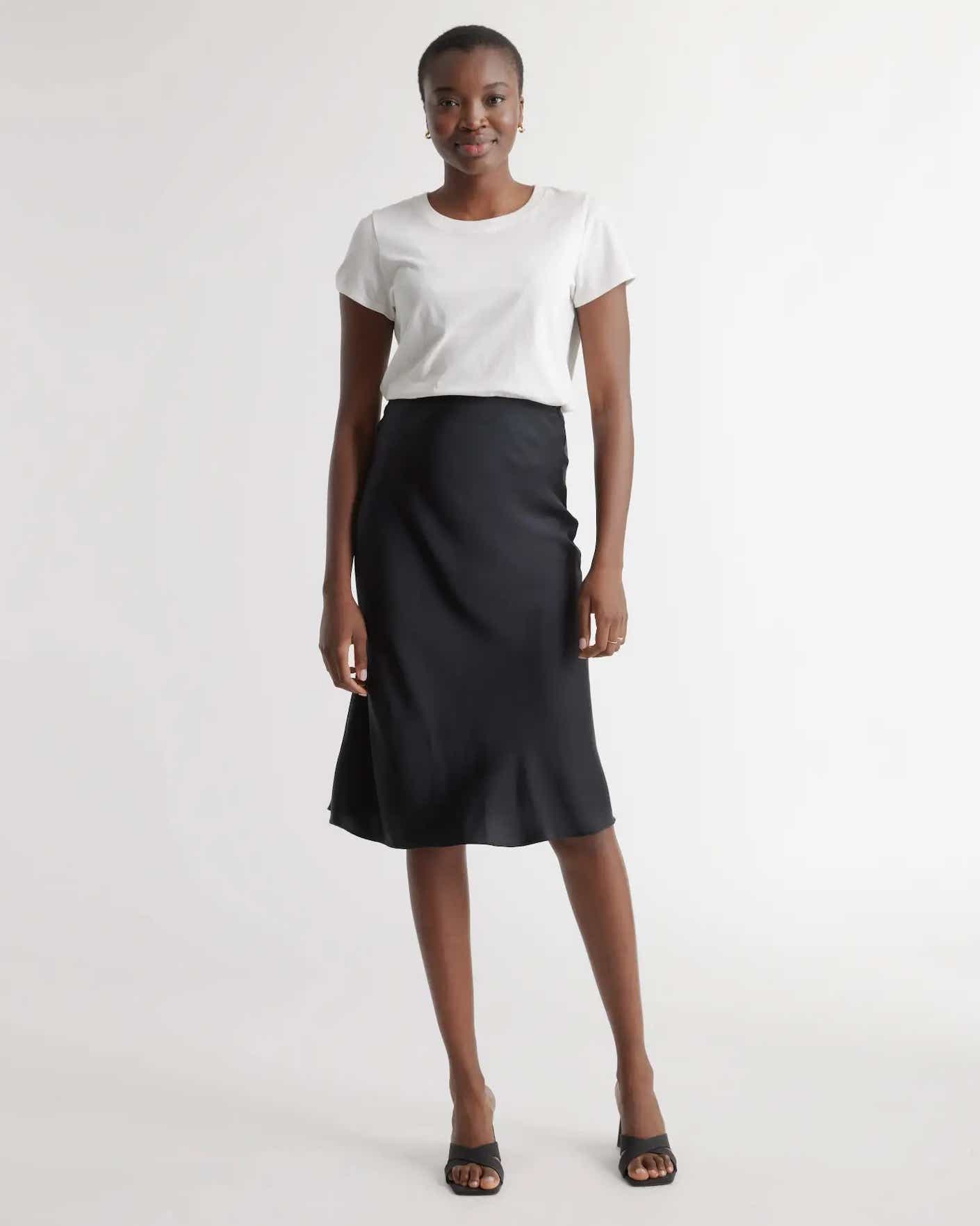 A woman wears a black, tea length skirt that is simply cut.
