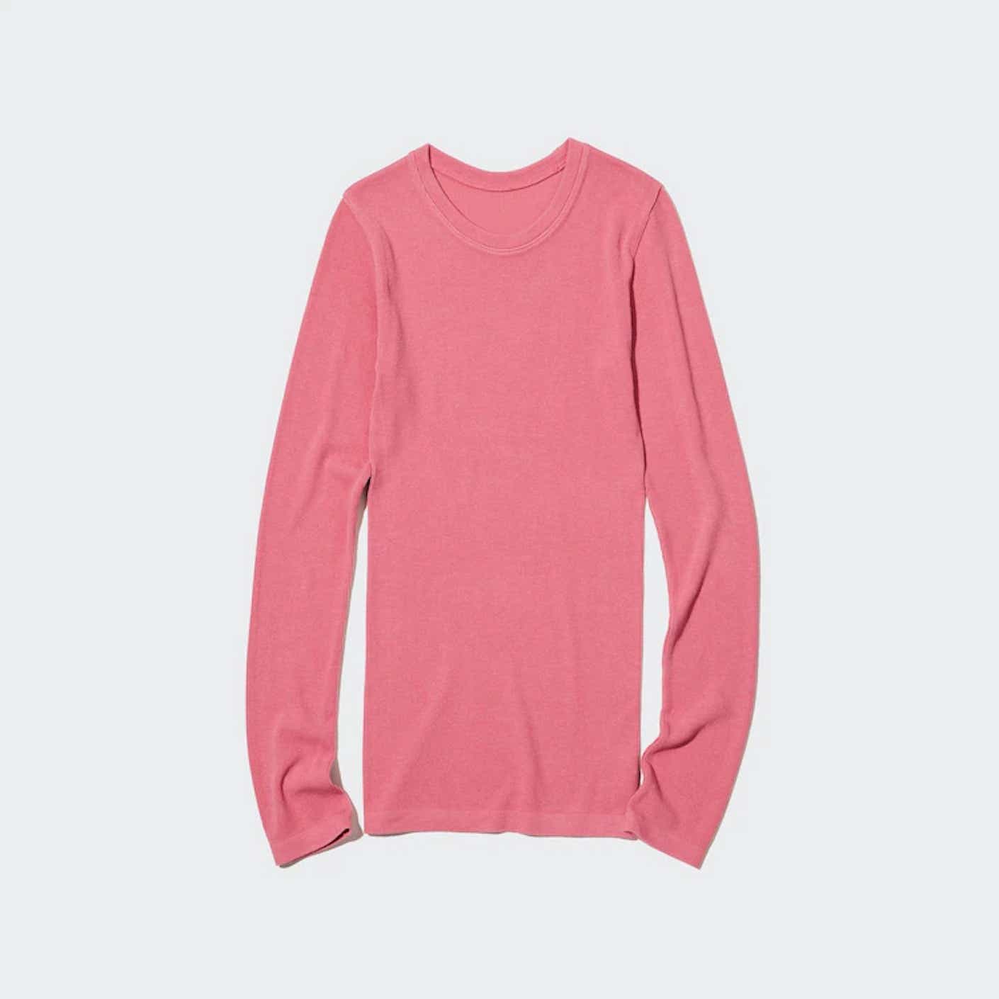 A long, long-sleeved, pink shirt is displayed on a flat, white surface.