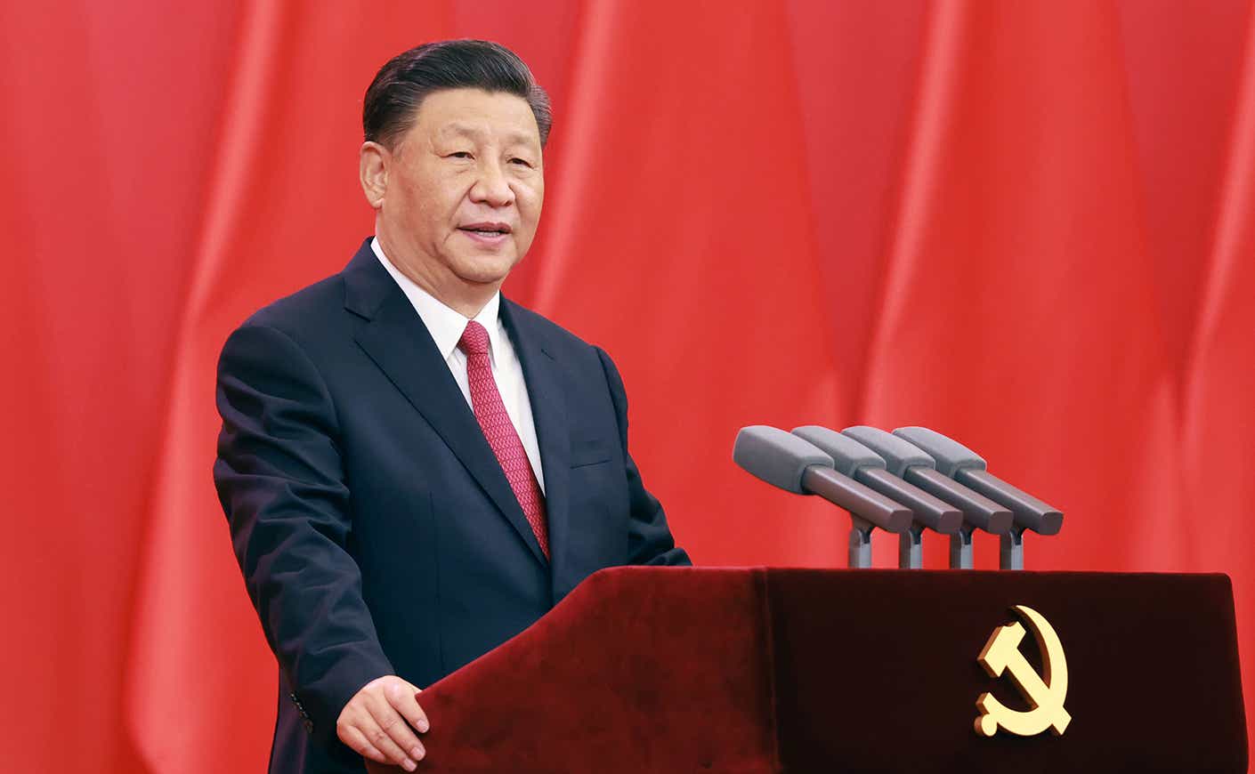Xi Jinping at podium in front of red curtain