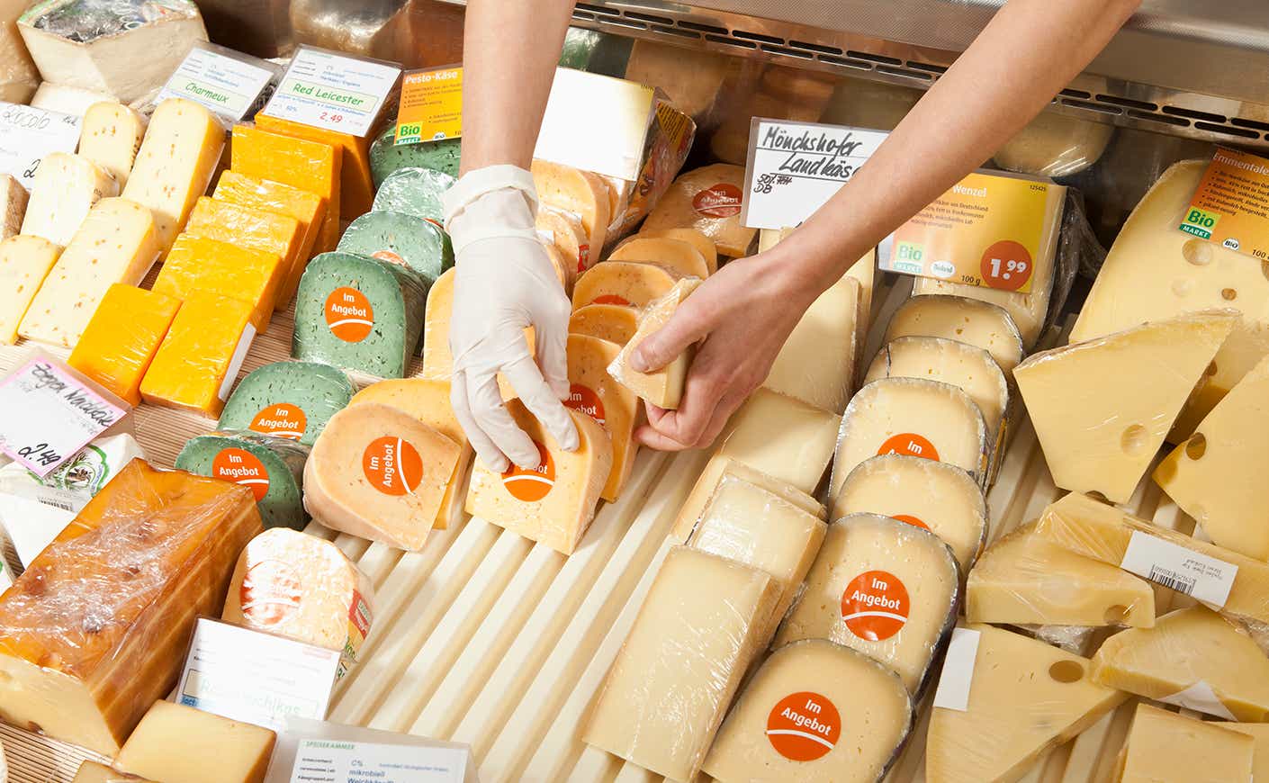 Hands reaching for cheese at deli counter