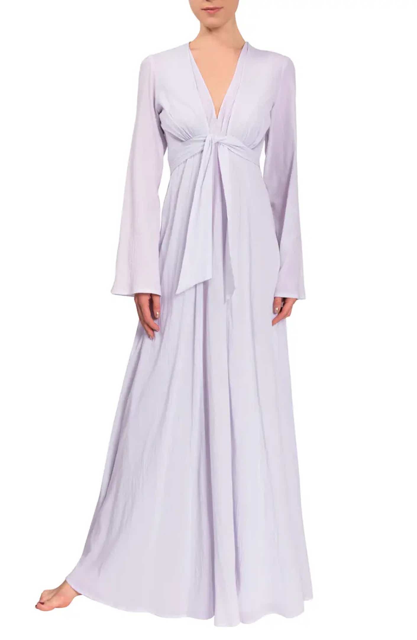 A woman wears a floor length, empire waisted cotton robe in front of a white background.