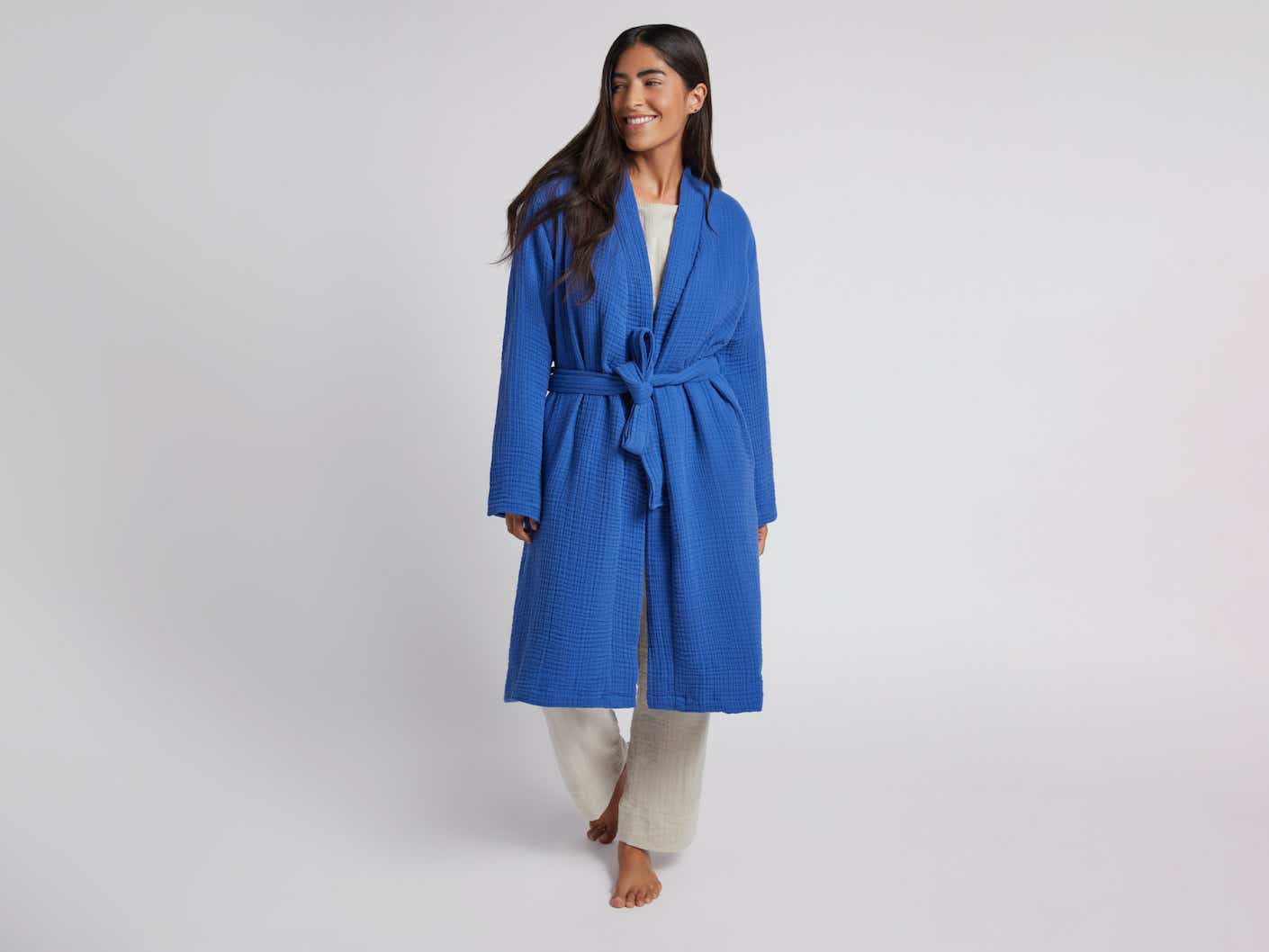 A woman wears a bright blue robe that falls beneath her knees.