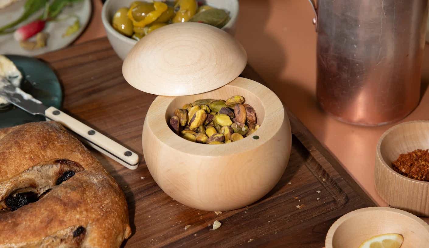 a wooden spherical salt well full of pistachios