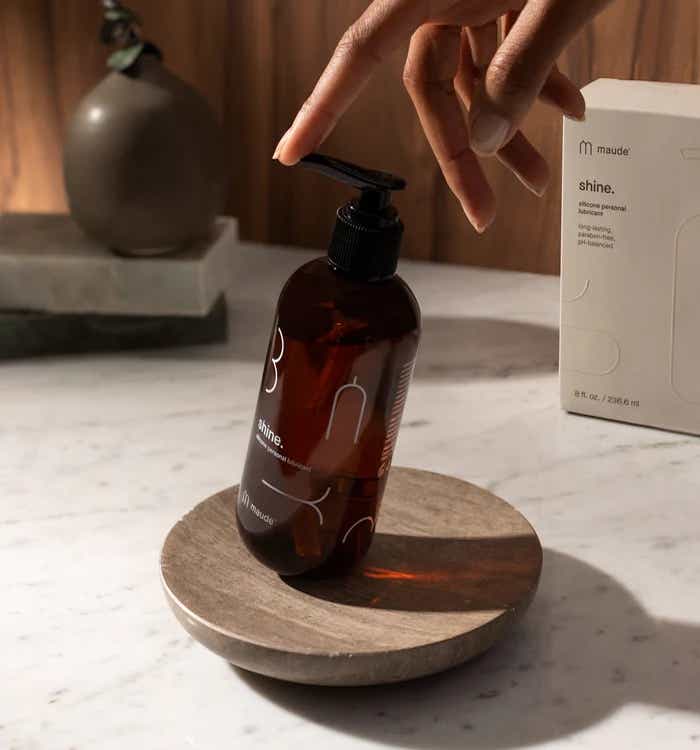 A person touches the top of a brown bottle of paraben-free lube.