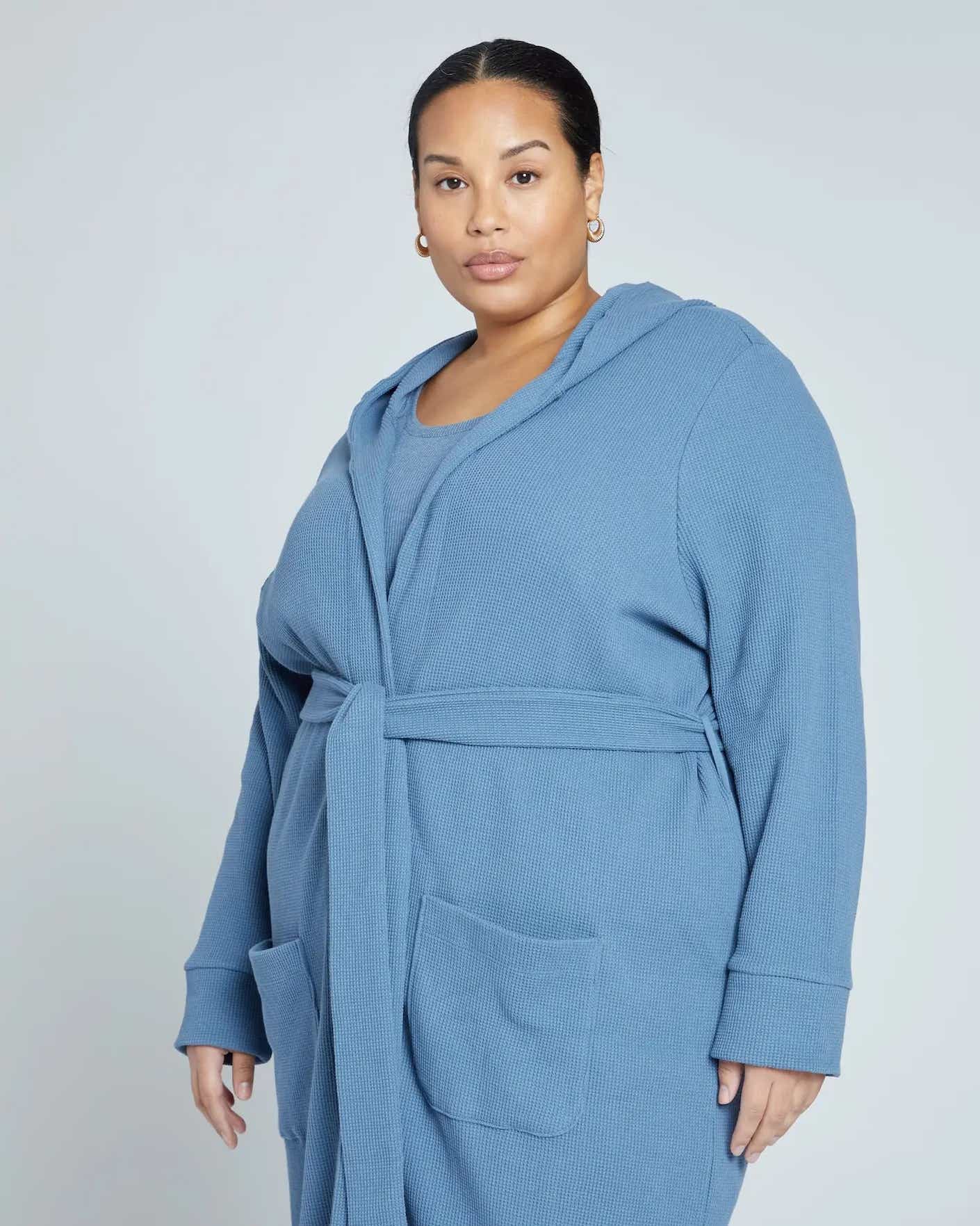 A woman wears a lightweight waffle knit robe in a creamy blue shade.
