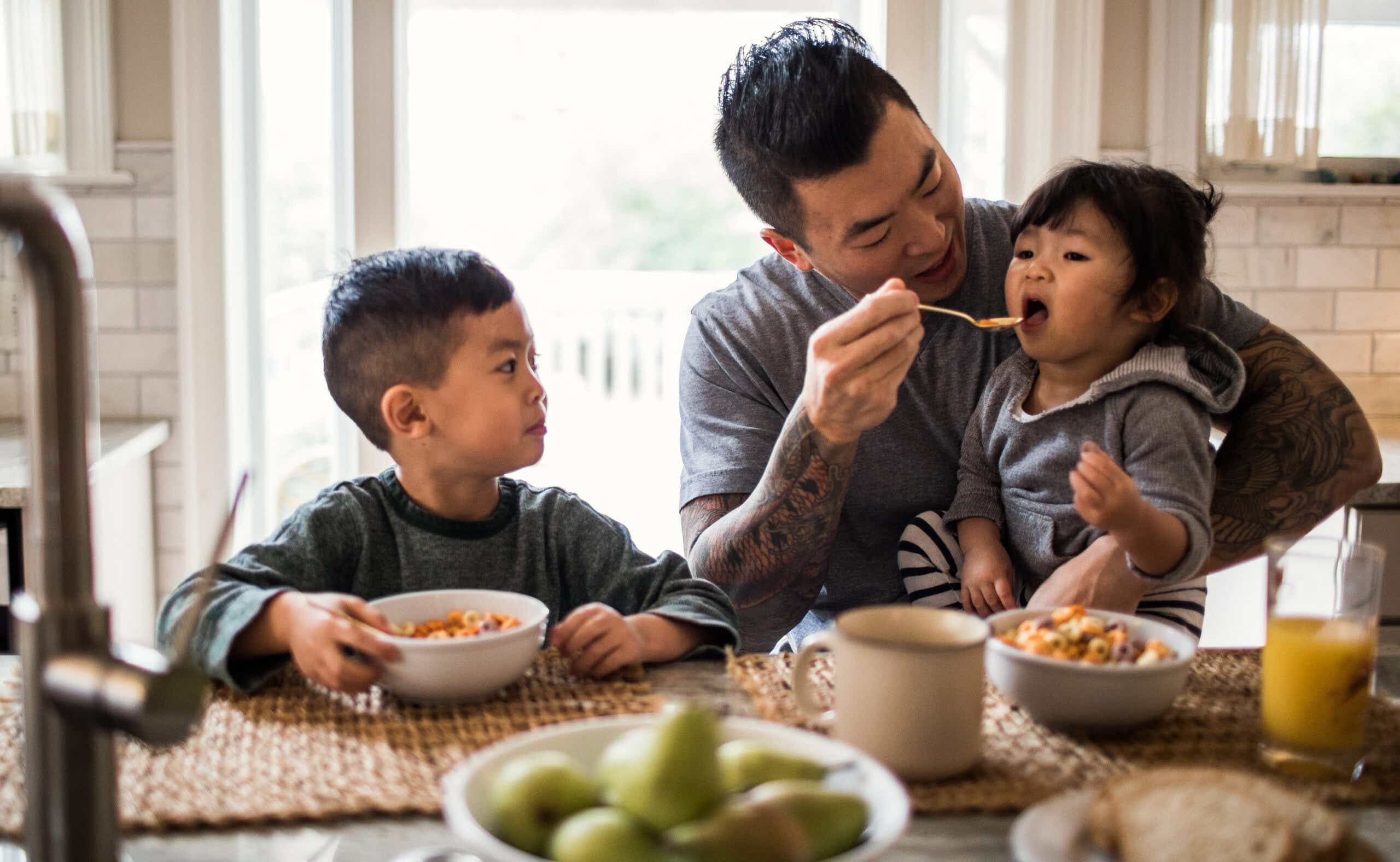 Dad feeding two small kids cereal