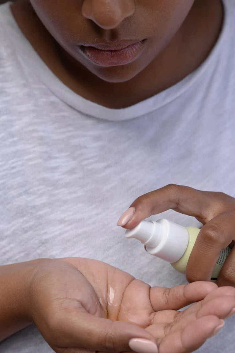 A woman sprays serum into her palm.