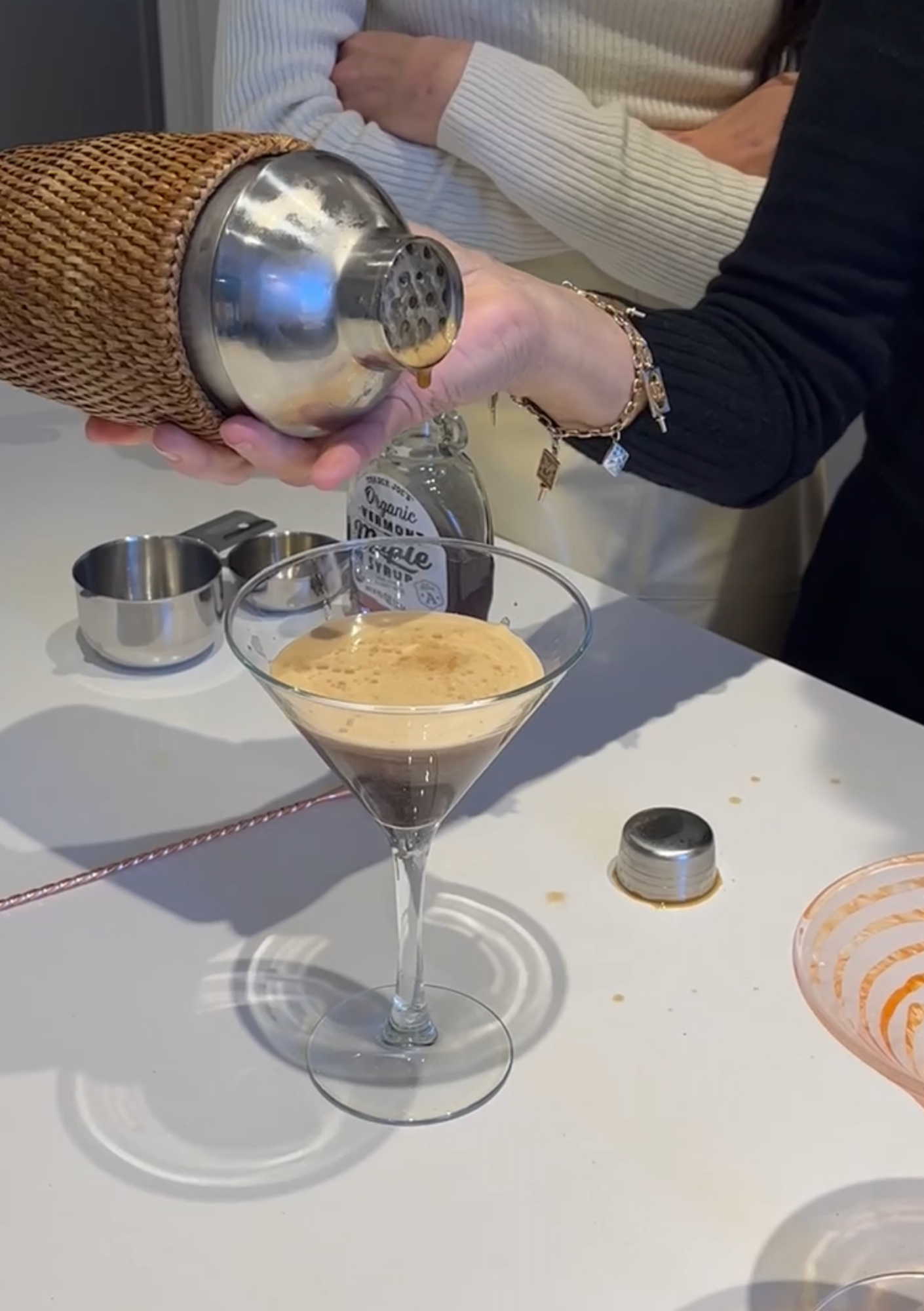 A frothy espresso martini sits on a white countertop.