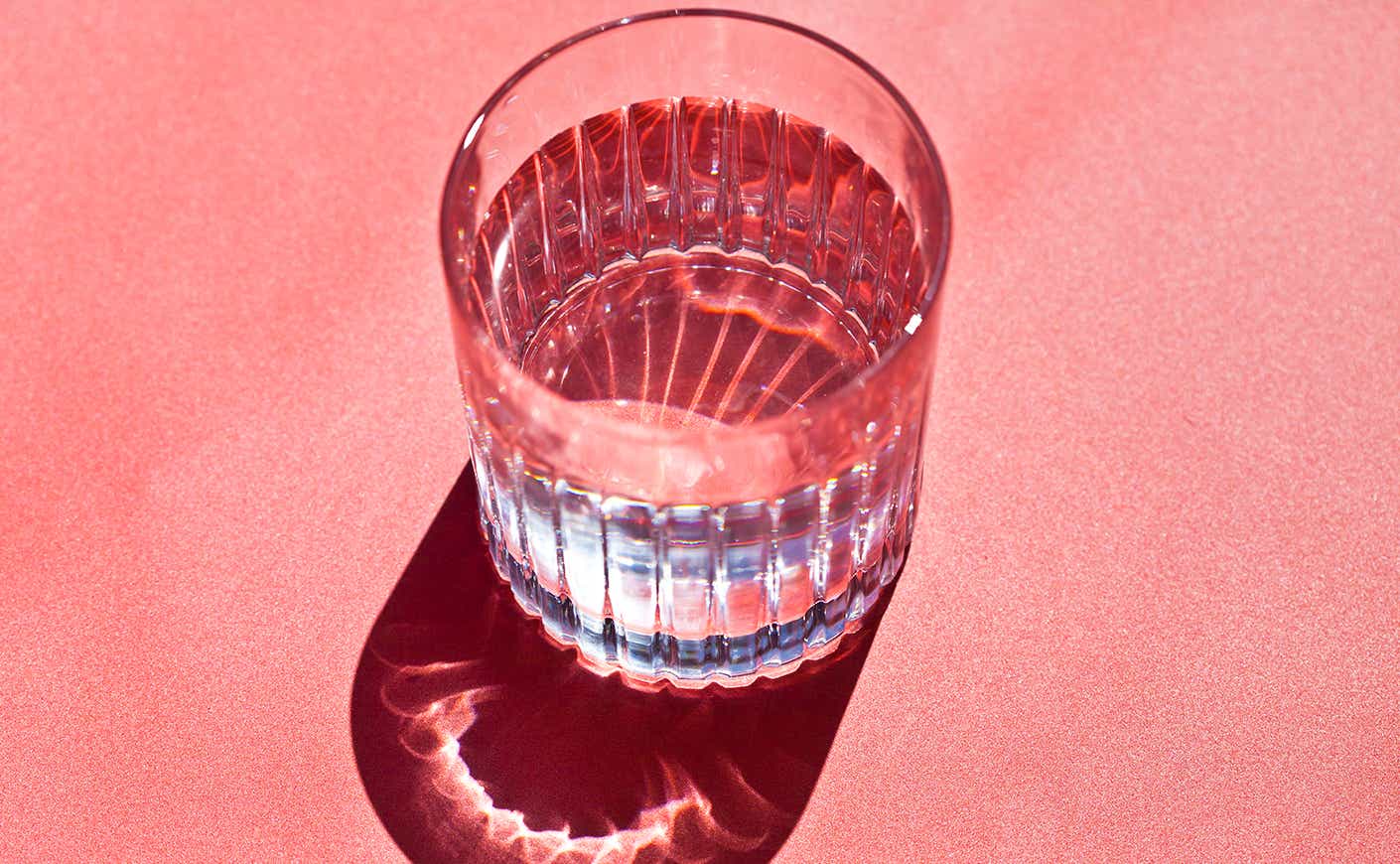 Cup of water on pink background