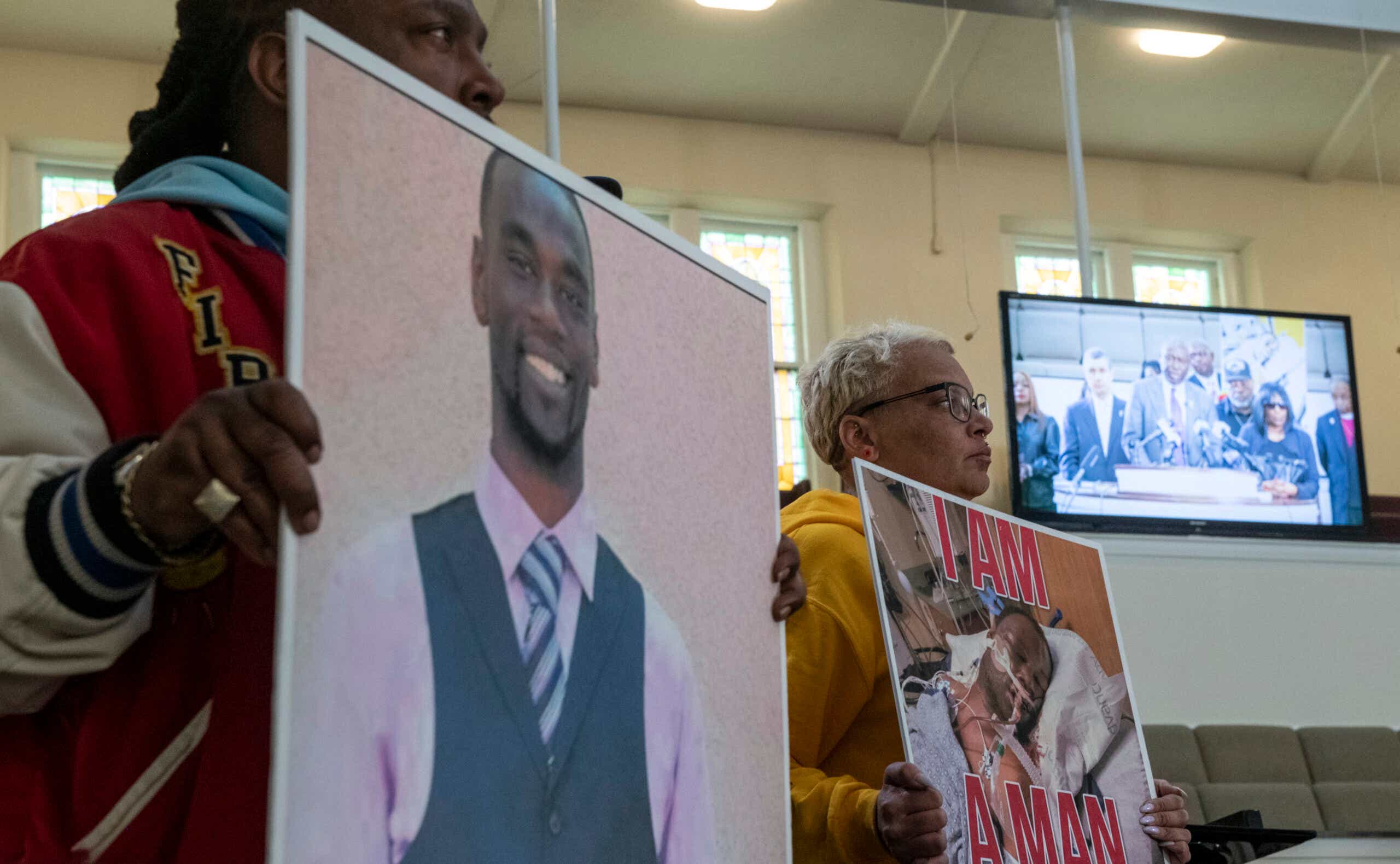 Activists hold signs showing Tyre Nichols