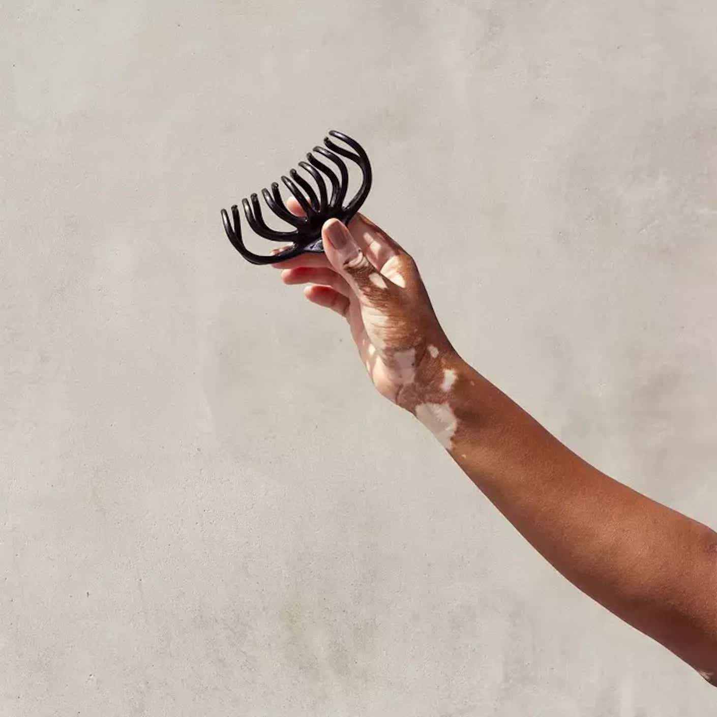 A woman's arm holds a black claw clip.