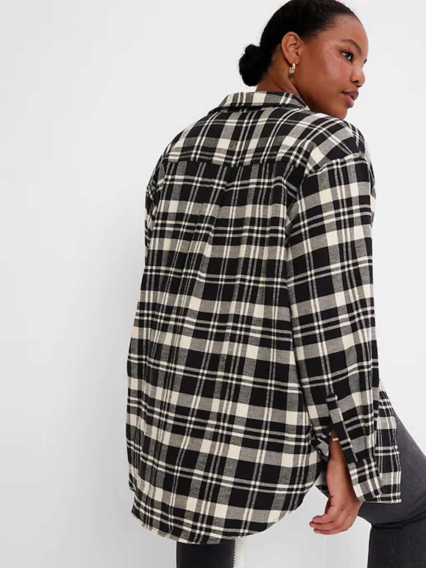 A woman wears a black and white flannel shirt.