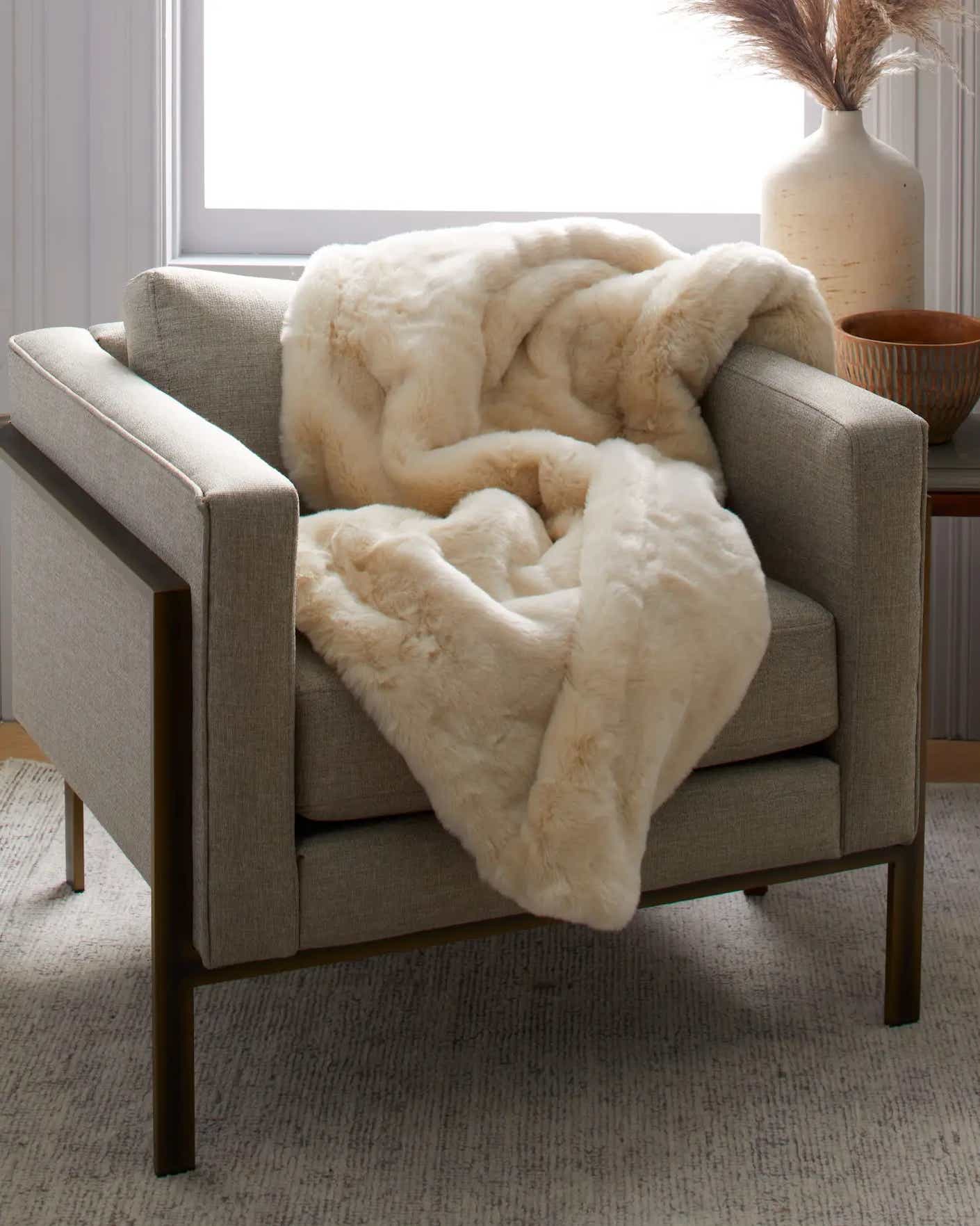 A fuzzy and plush fur throw lies thrown across a chair.