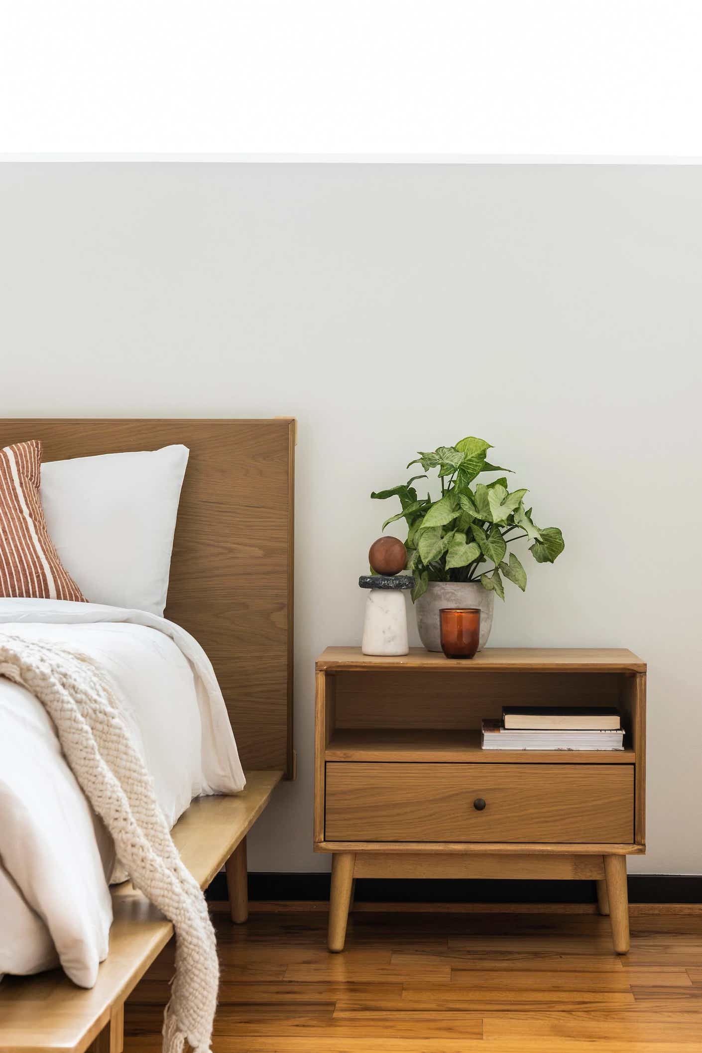 A sleek and minimalistic nightstand is pictured next to a clean white bed.