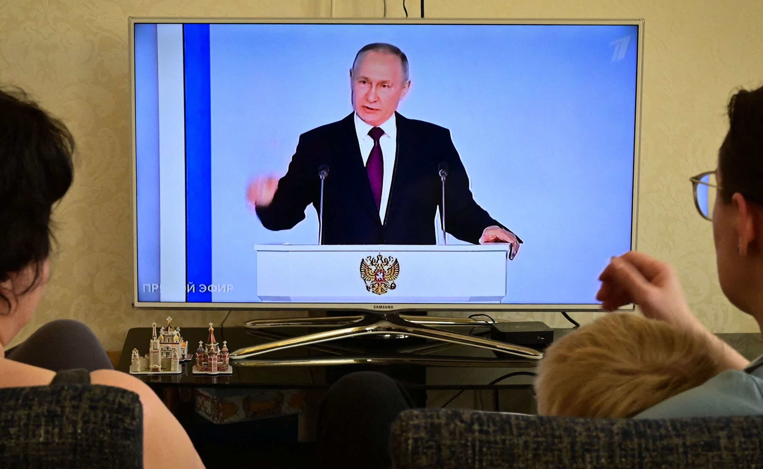 A family watches a TV broadcast of Russian President Vladimir Putin's address