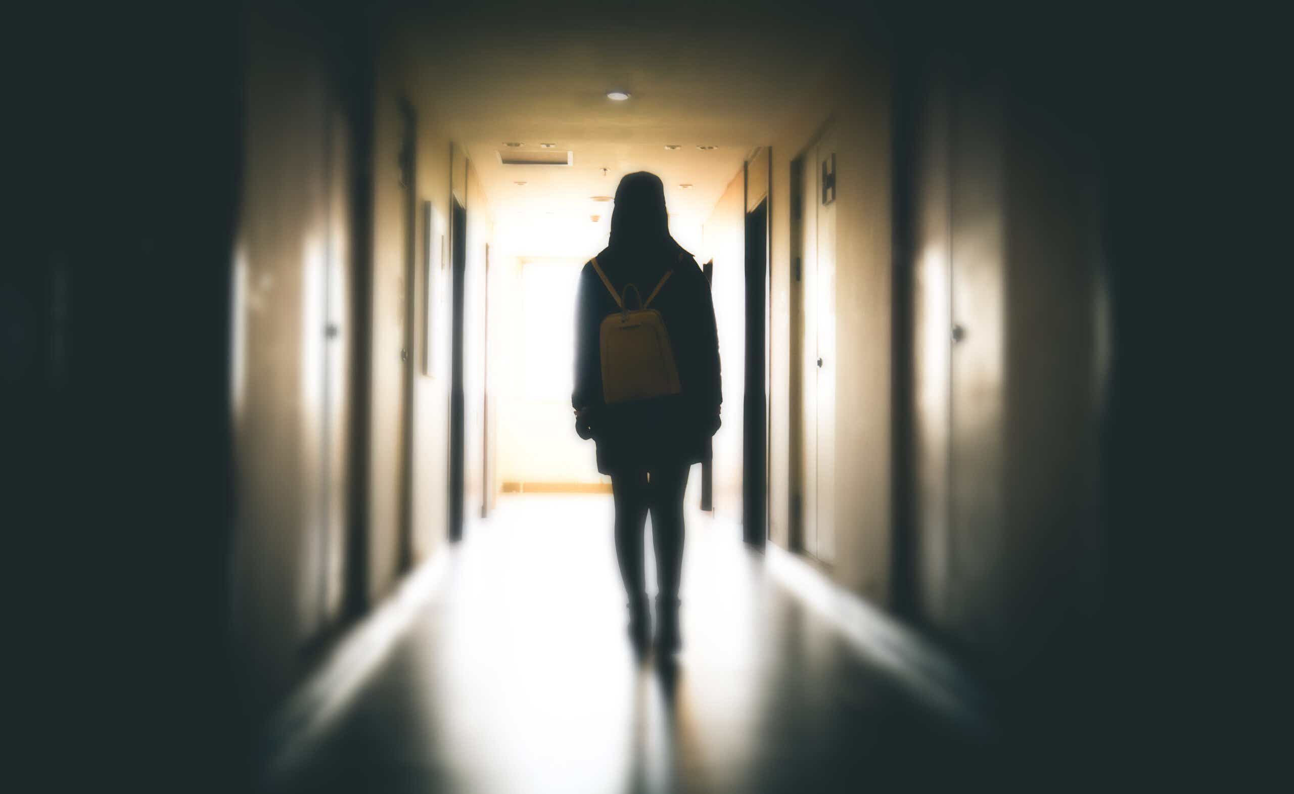 Teen girl in shadowy hallway from behind