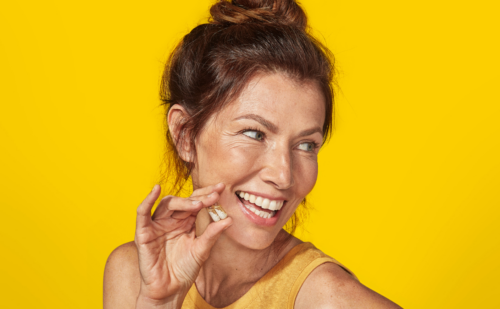 Woman holding Ritual vitamins on a yellow background