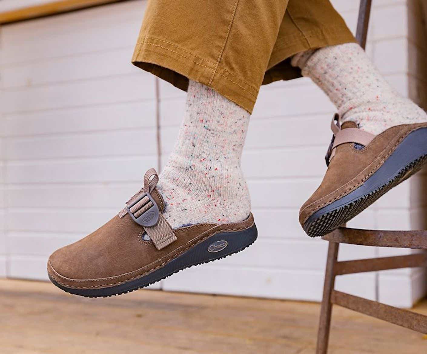 a personn wears a pair of clogs with oatmeal colored socks.