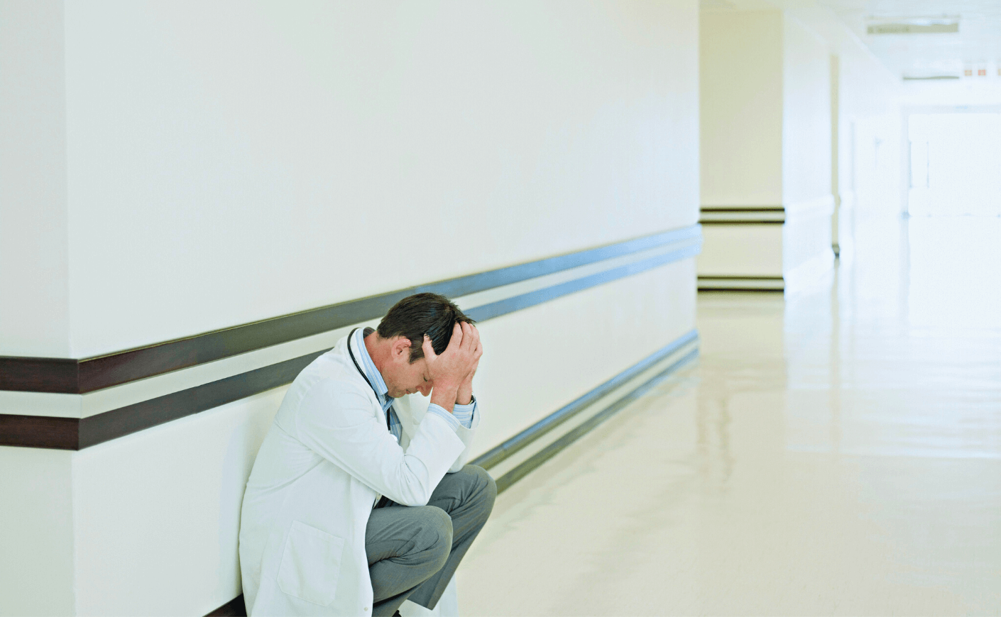 a doctor bent over in a hospital hallway