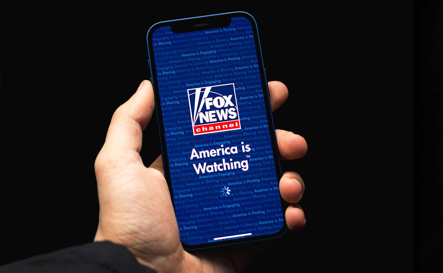 Hand holding phone with Fox News pulled up