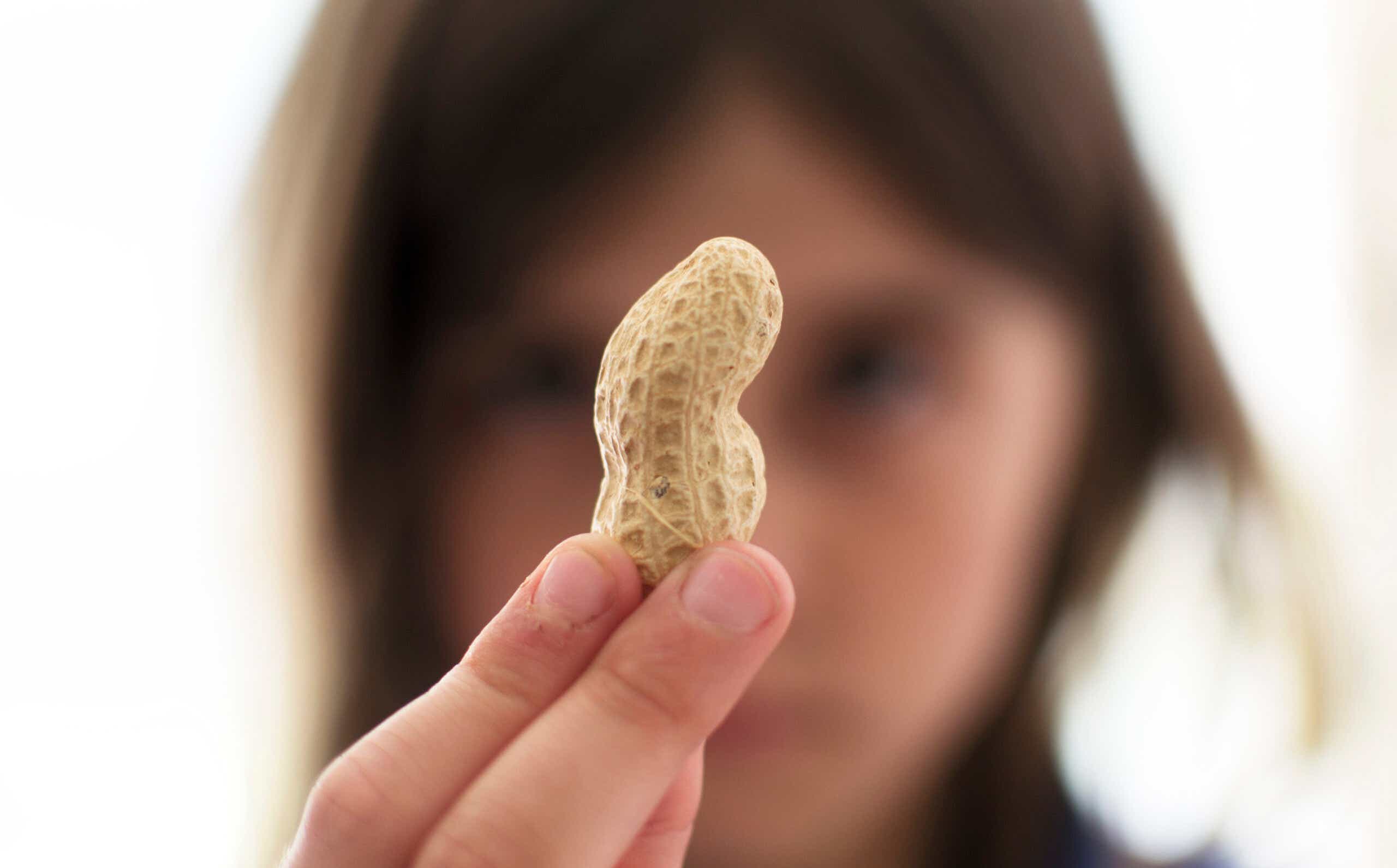 A young child holds up a peanut looks at it closely.