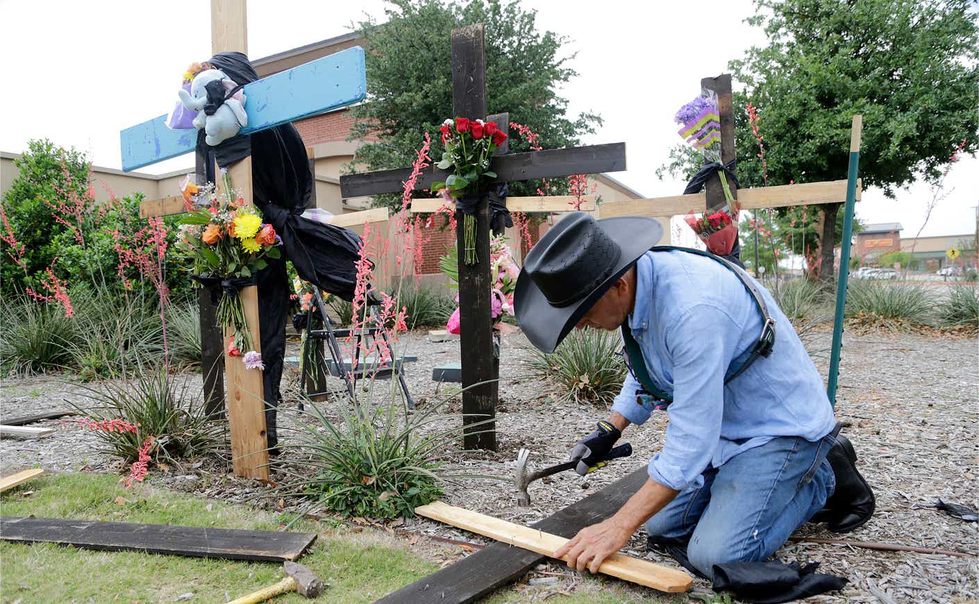 a man erects crosses for those killed in Allen, Texas