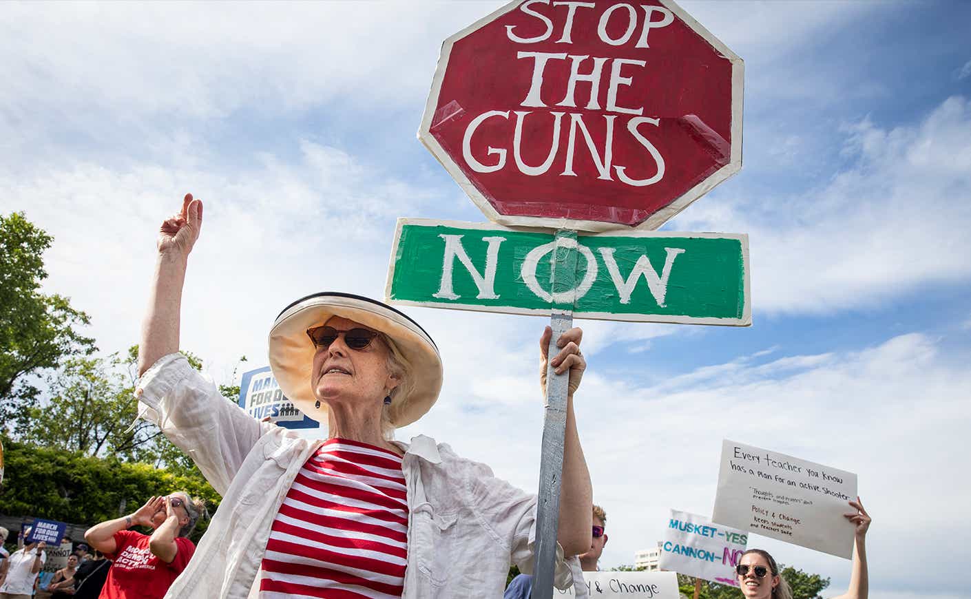 woman holding up sign saying "stop the guns now"
