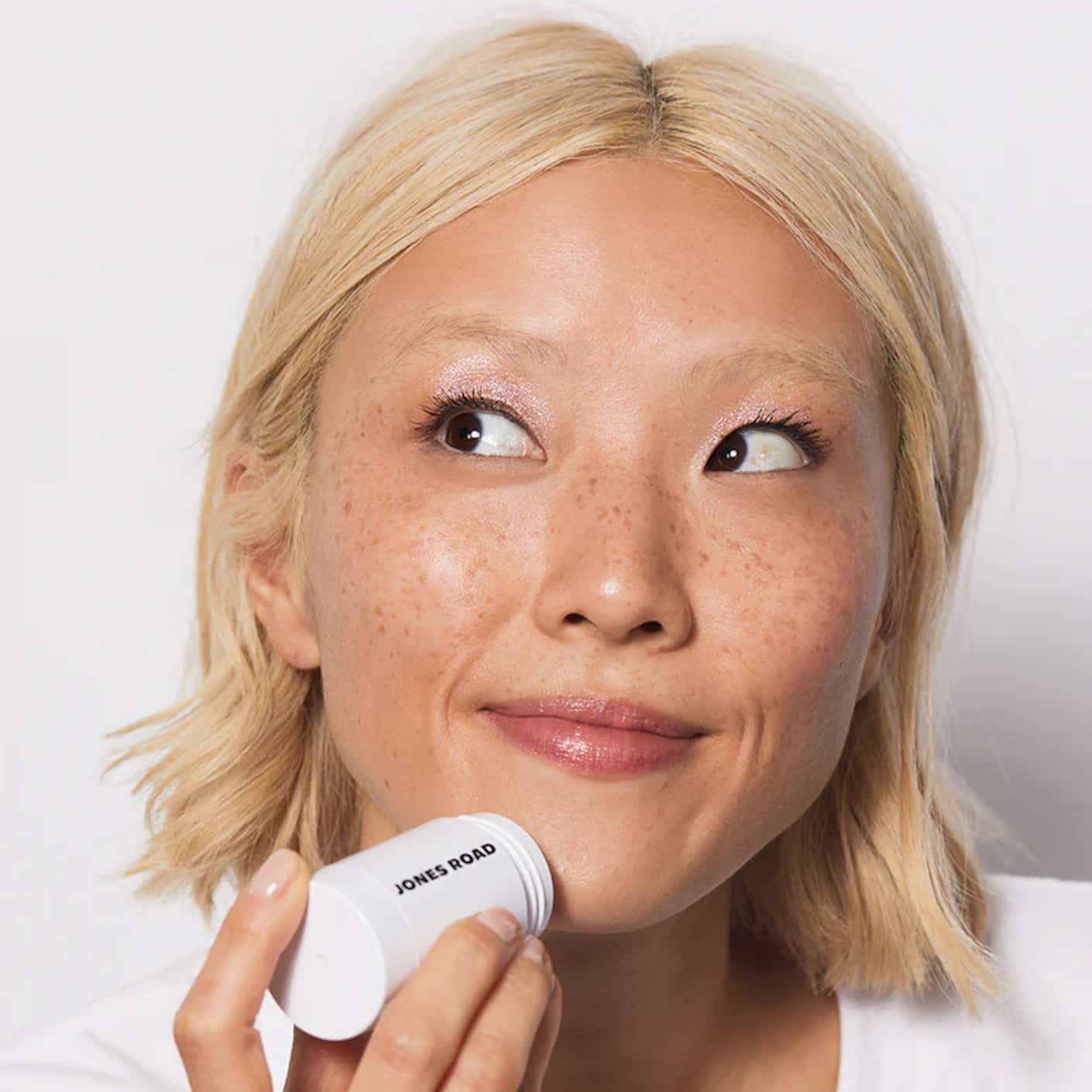 A woman applies cleanser with a stick