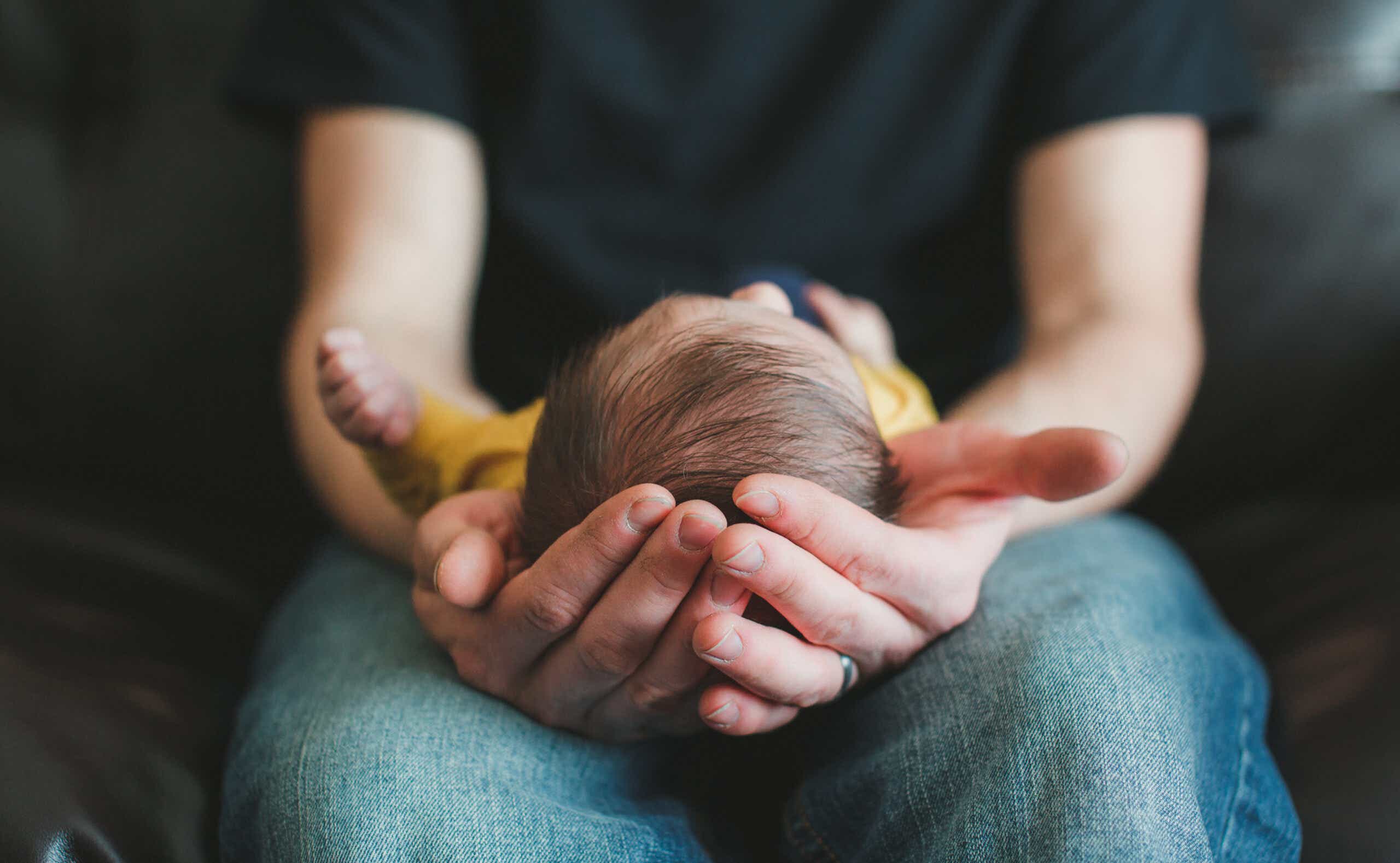 Father's hands holding newborn