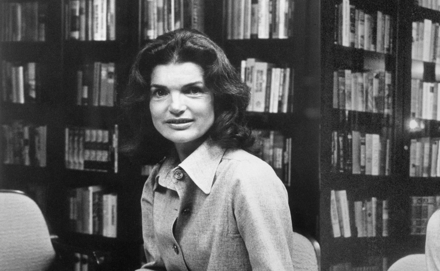 Jackie Kennedy sits in front of bookshelves