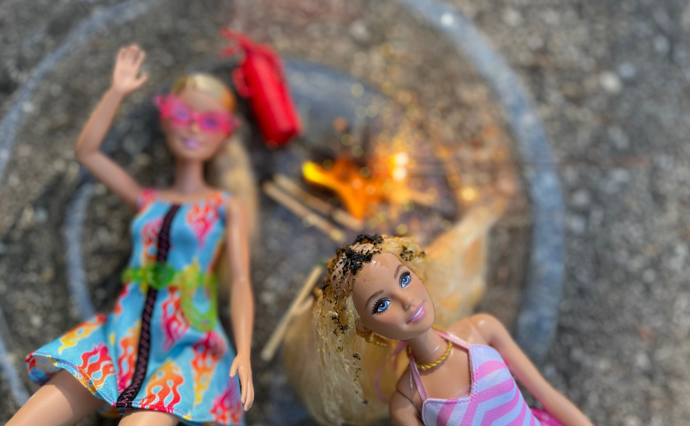 A pair of charred Barbies next to matches and a flame
