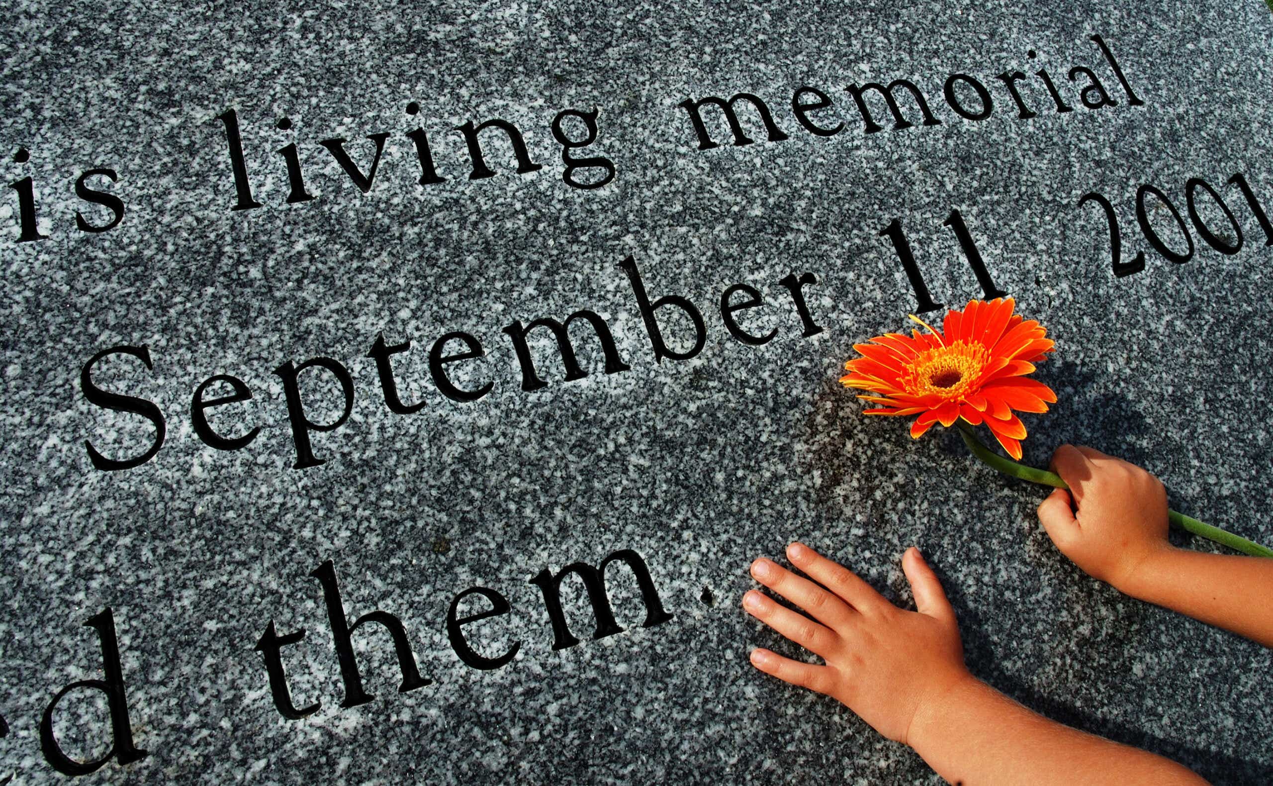 a flower and child's hands on the 9/11 memorial