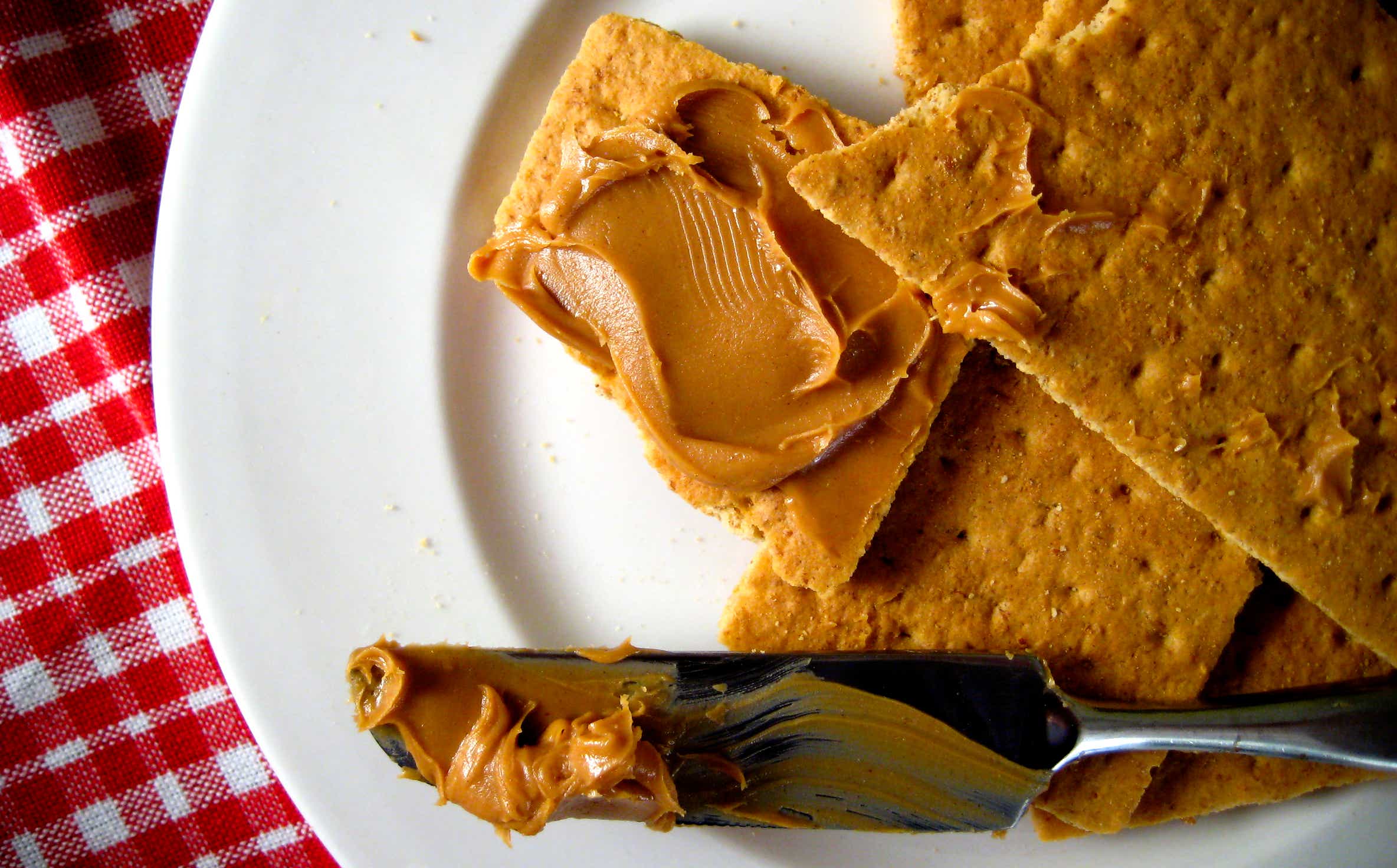 Peanut butter and graham crackers on red background