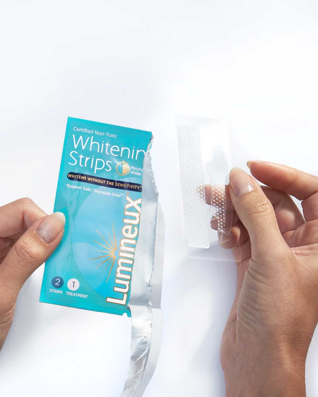 hands unwrapping lumineux whitening strips