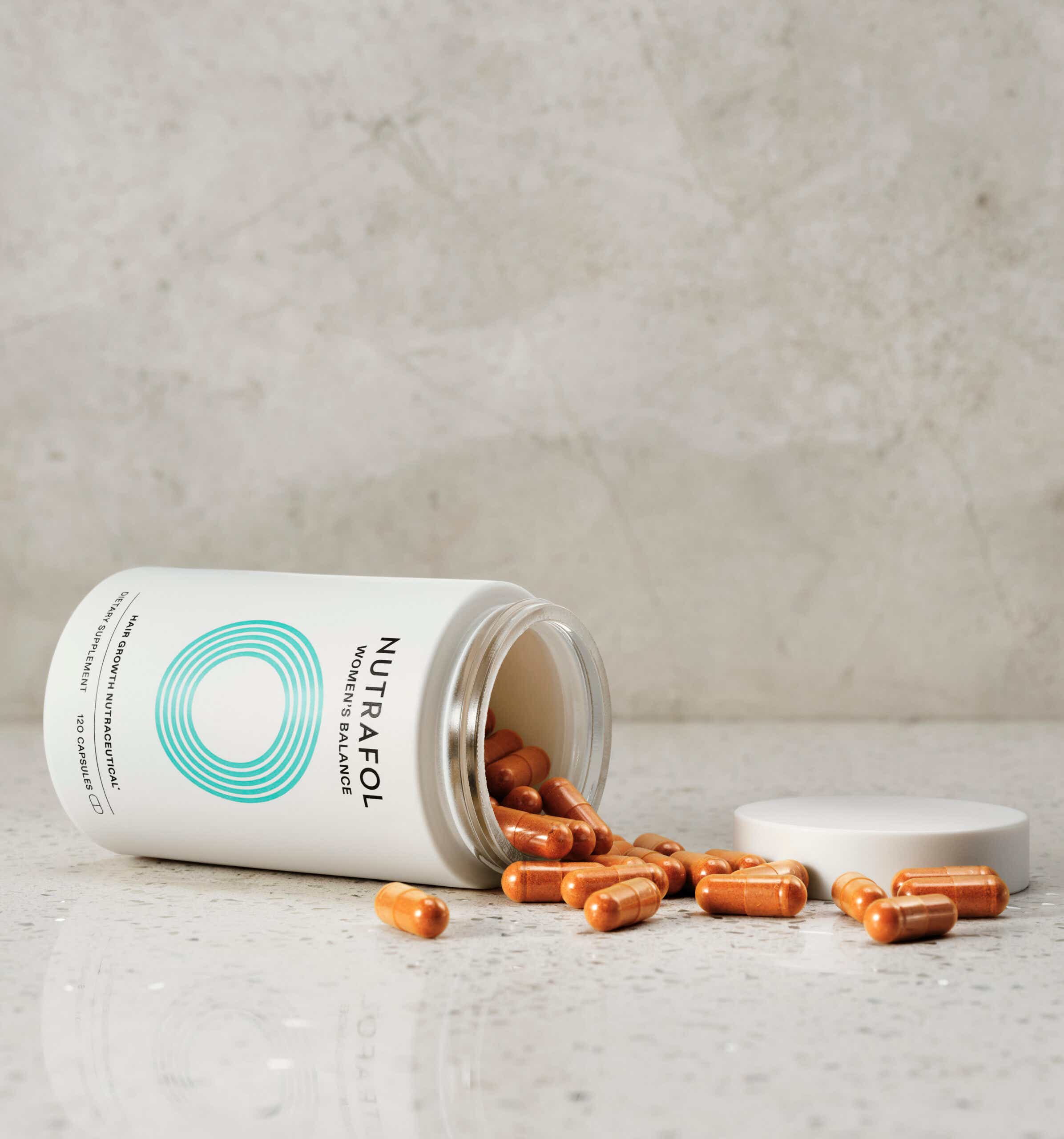 Nutrafol Balance Capsules spilling out of jar