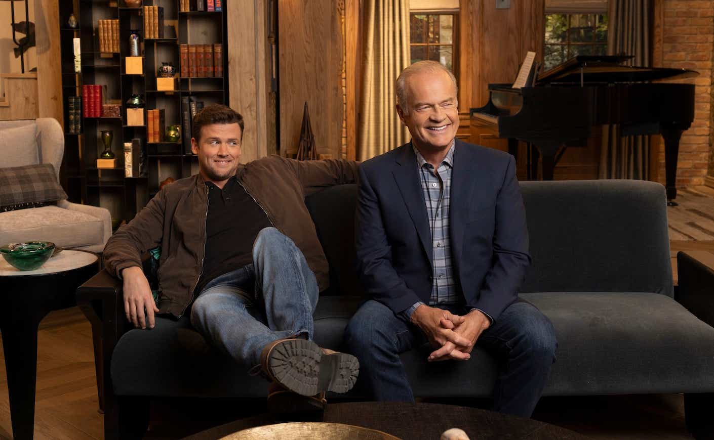 kelsey grammer and his costar sitting on a couch on the set of the frasier reboot
