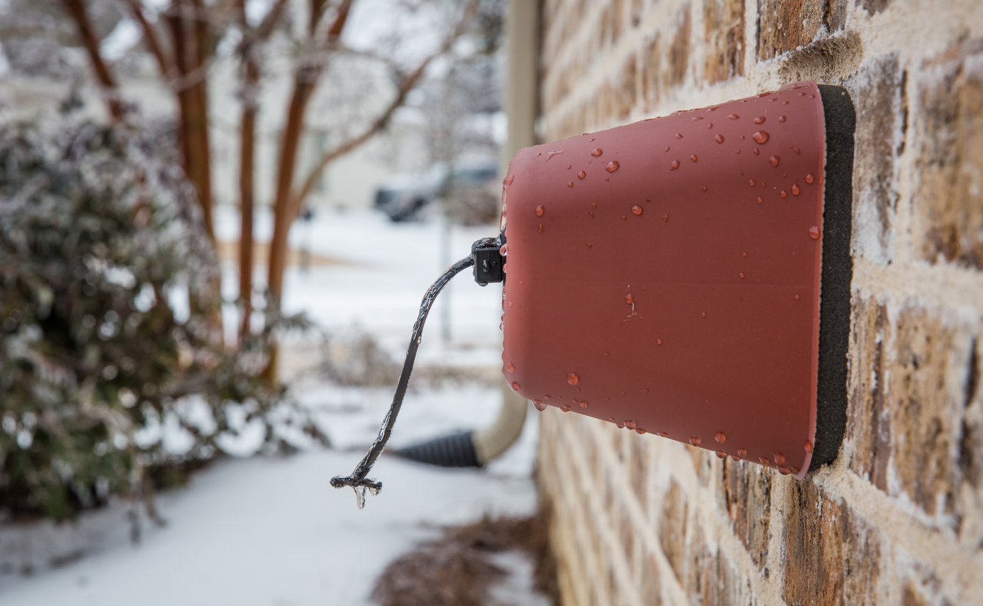 A faucet cover outside a house during winter